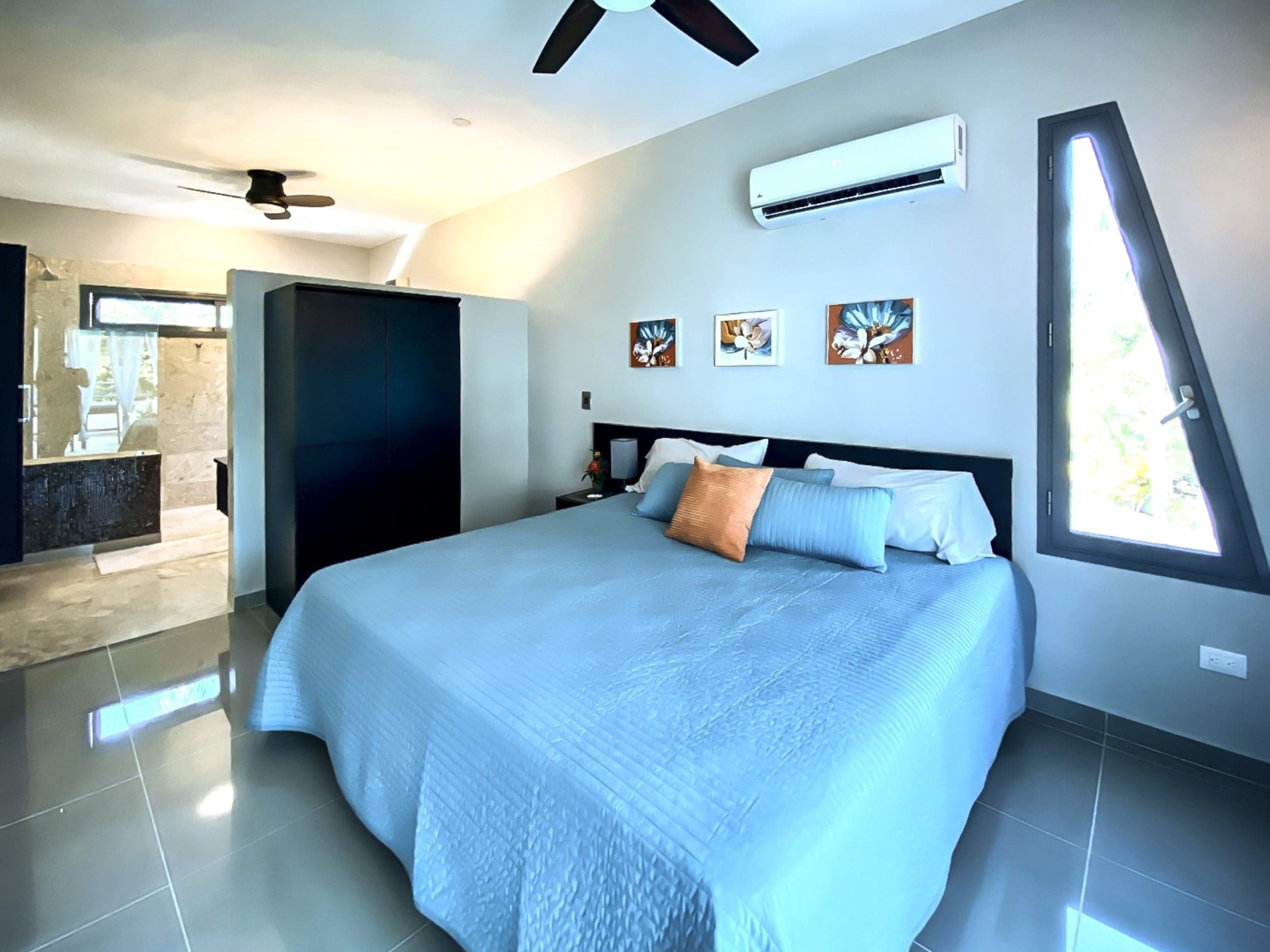 buyDRproperty Modern bedroom in a ProCab penthouse for sale, featuring blue bedding and a unique window. Sosua Real Estate