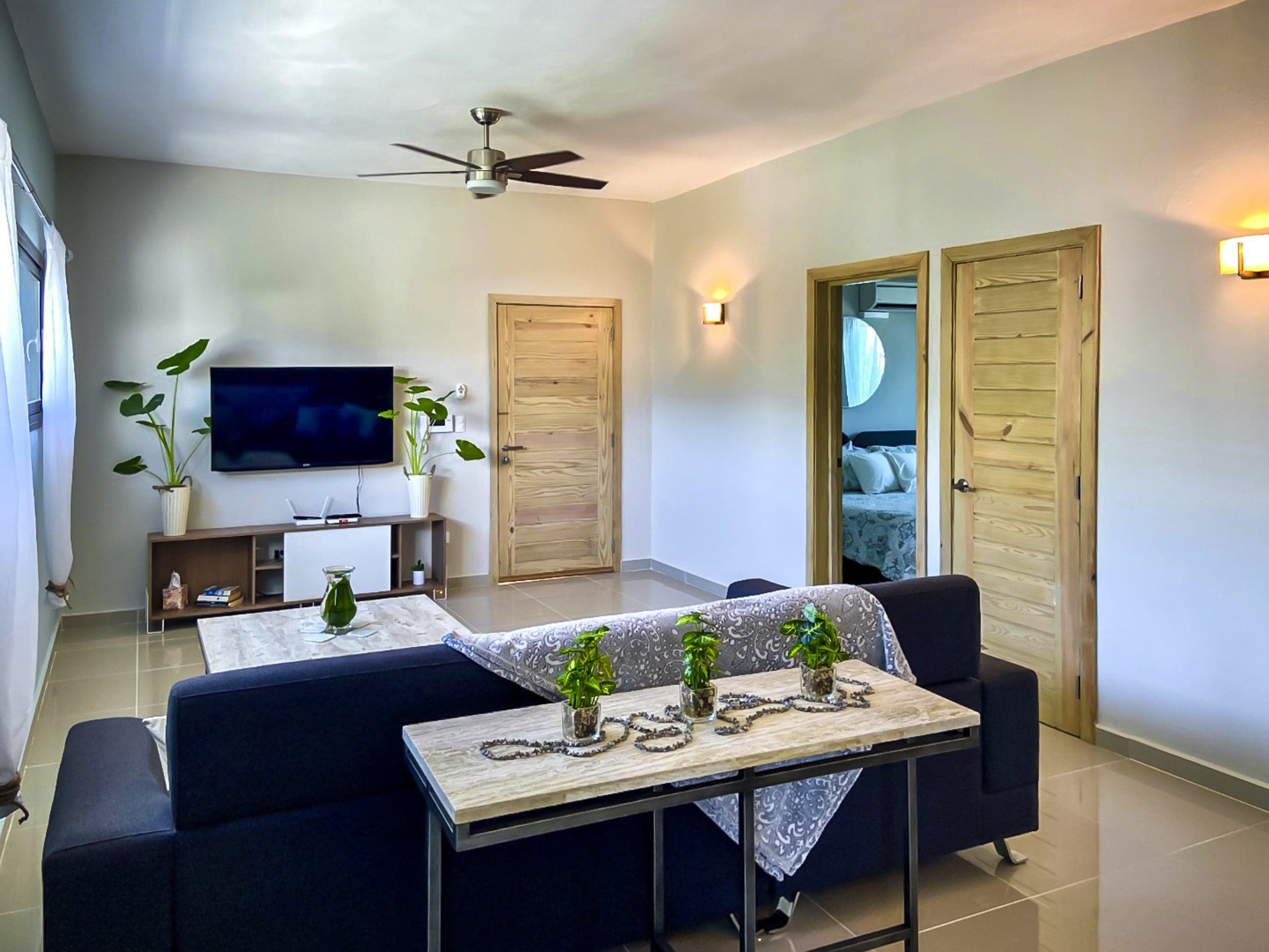 buyDRproperty Modern living room with dark blue sofa, TV, and wooden doors. Potential for sale in ProCab. Sosua Real Estate