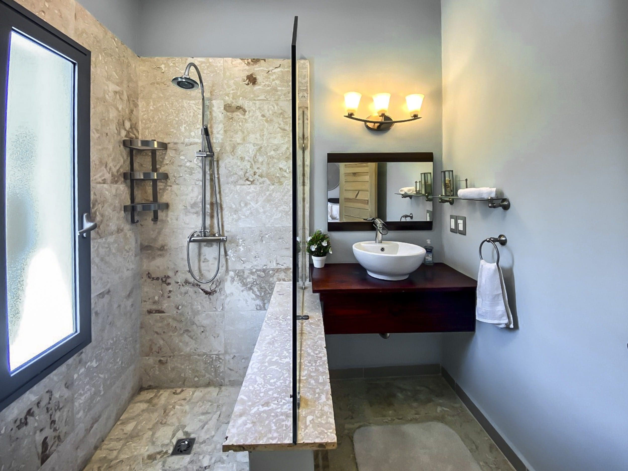 buyDRproperty Modern bathroom with glass shower, floating vanity, and marble tile. Sosua Real Estate