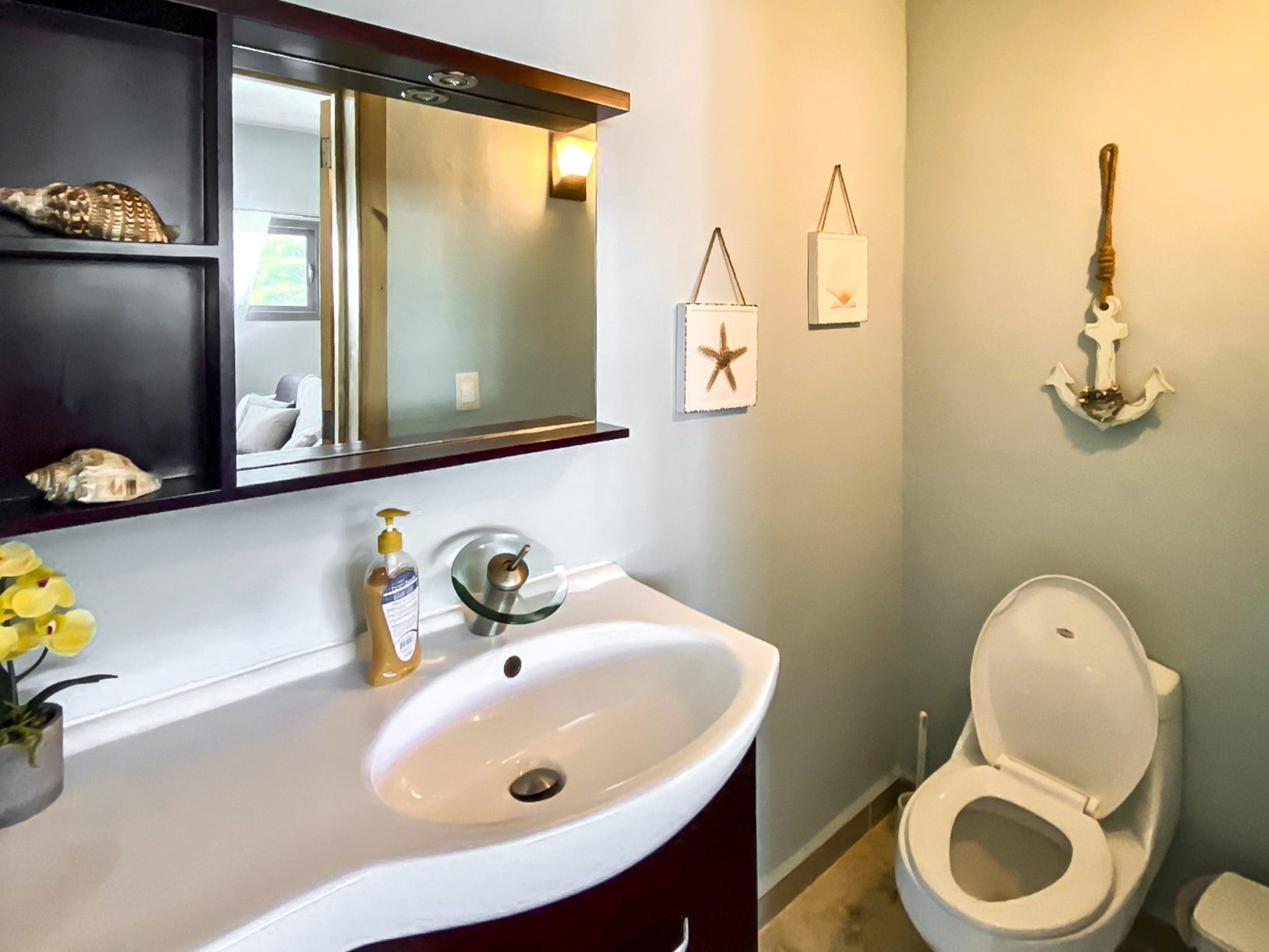 buyDRproperty Coastal bathroom with sink, toilet, and decorative starfish art. Located in a ProCab penthouse. Sosua Real Estate