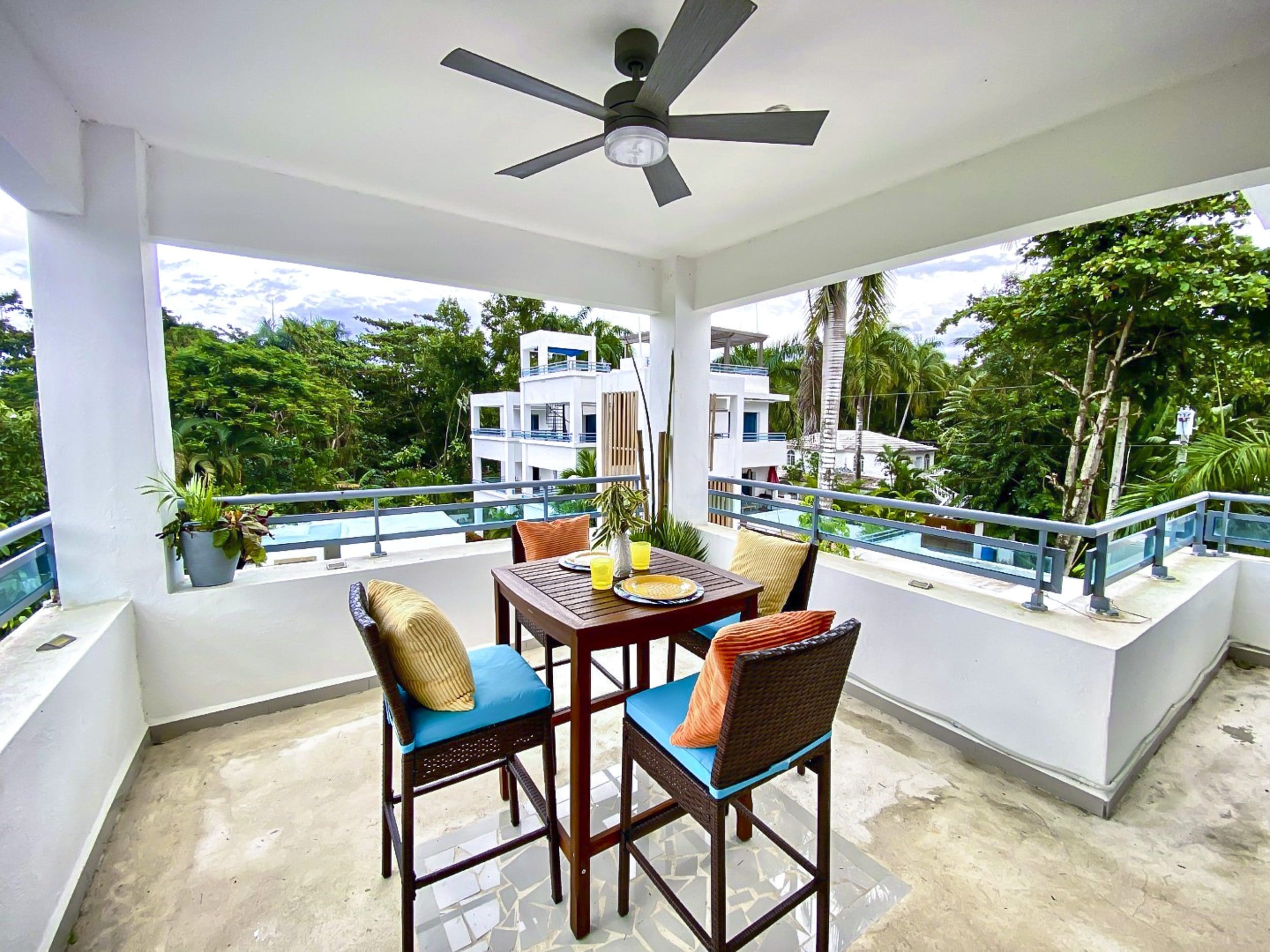 buyDRproperty Balcony dining set with view of lush greenery and a building in ProCab. Sosua Real Estate