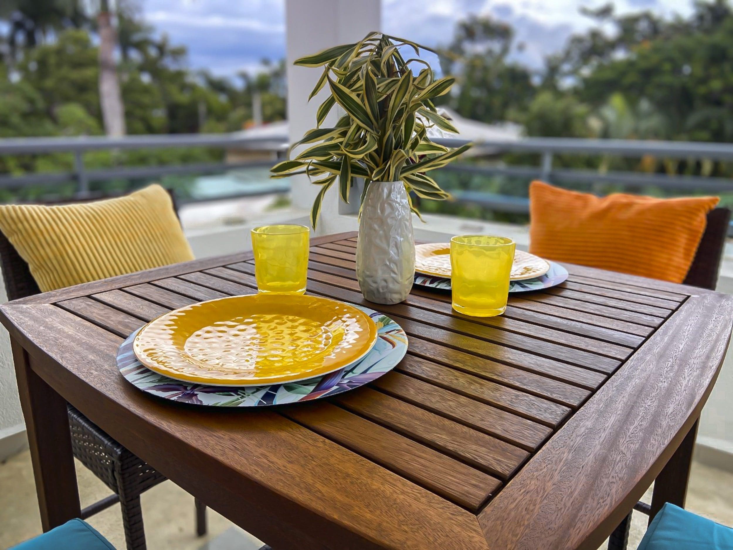 buyDRproperty Outdoor dining table set with plates, glasses, and a vase of plants, creating a relaxing atmosphere. Sosua Real Estate