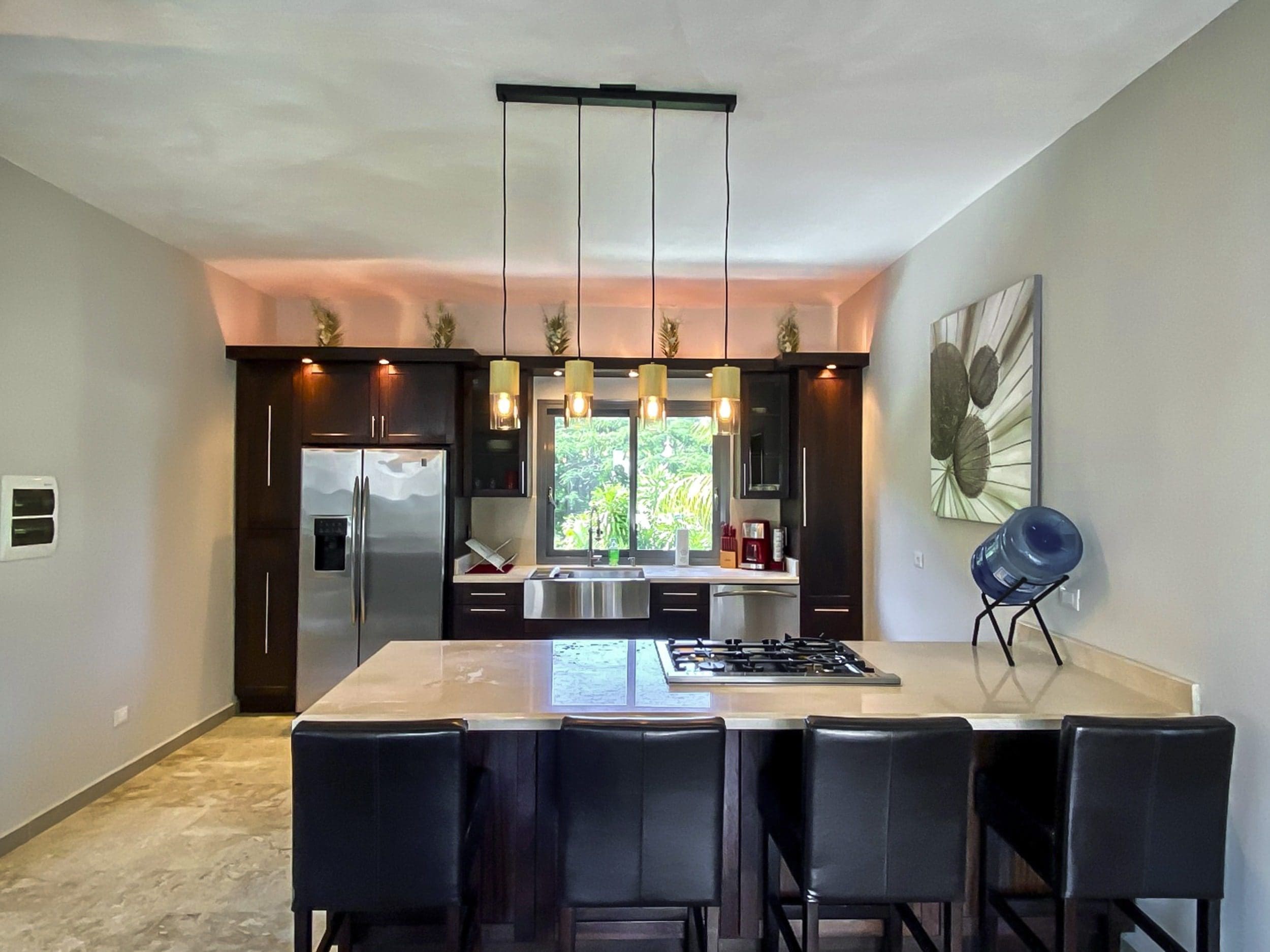 buyDRproperty Modern kitchen with dark cabinets, stainless steel appliances, and a breakfast bar with seating. Sosua Real Estate