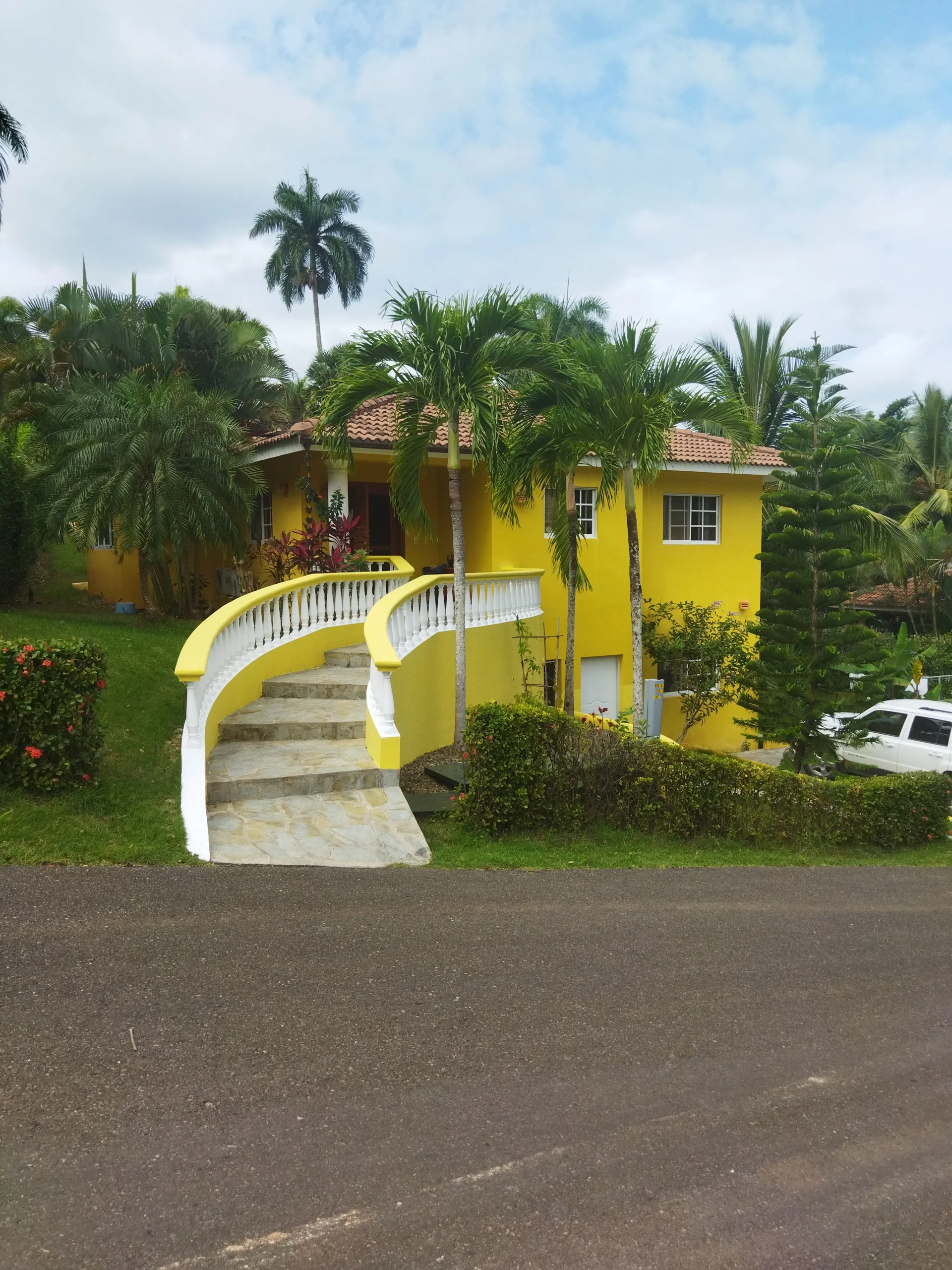 buyDRproperty Charming yellow villa with curved staircase and palm trees. Sosua Real Estate