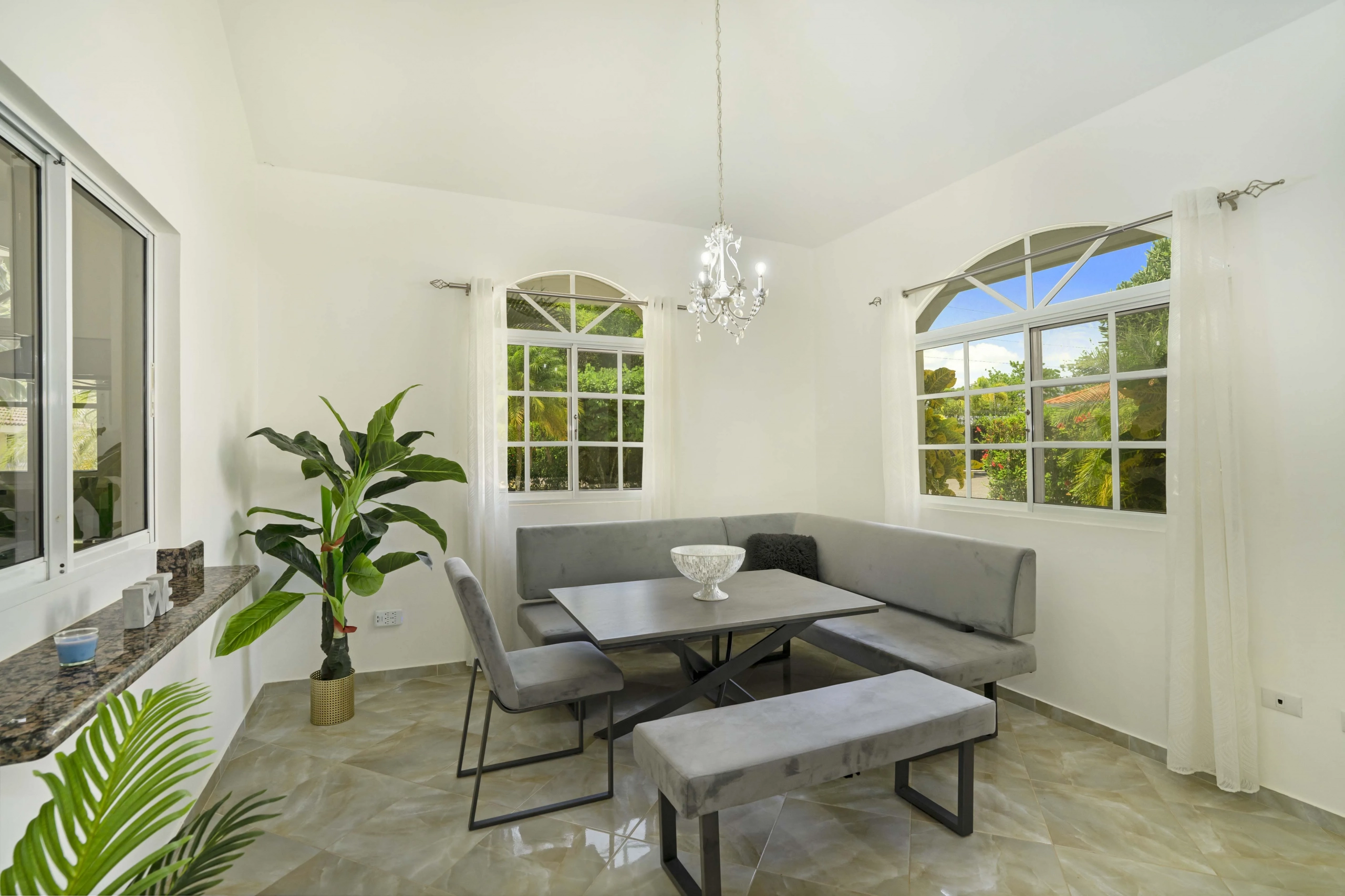 buyDRproperty Dining area in a beautiful villa with gray seating, a table, and a chandelier. Sosua Real Estate