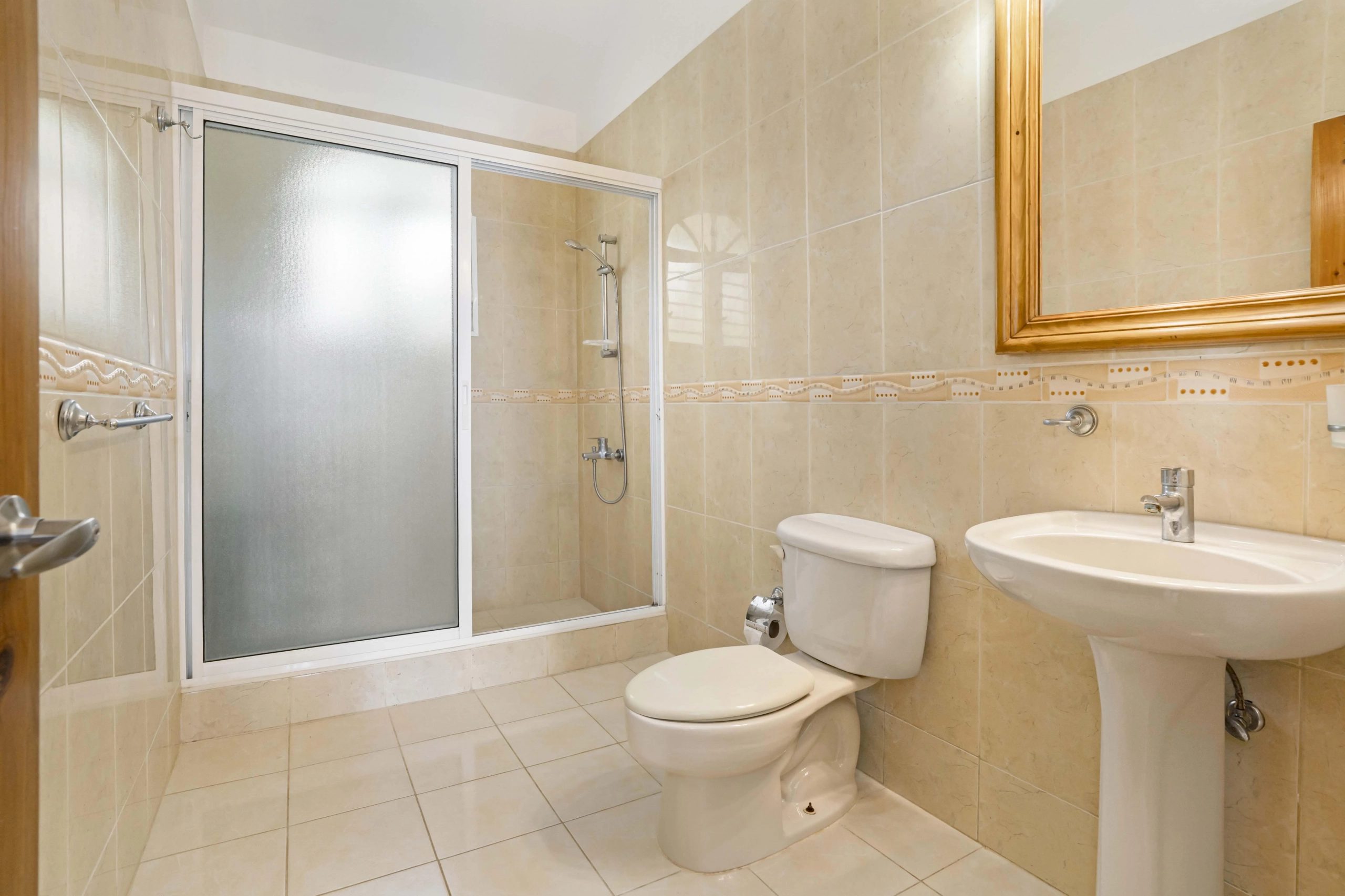 buyDRproperty Bathroom with shower, toilet, and sink, featuring tiled walls and floor. Sosua Real Estate