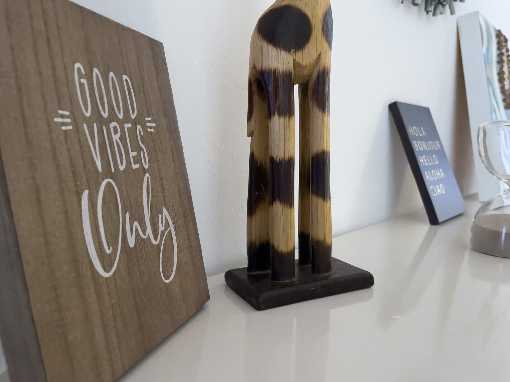 buyDRproperty Good Vibes Only sign, wooden giraffe, and travel-themed decor on a shelf. Sosua Real Estate