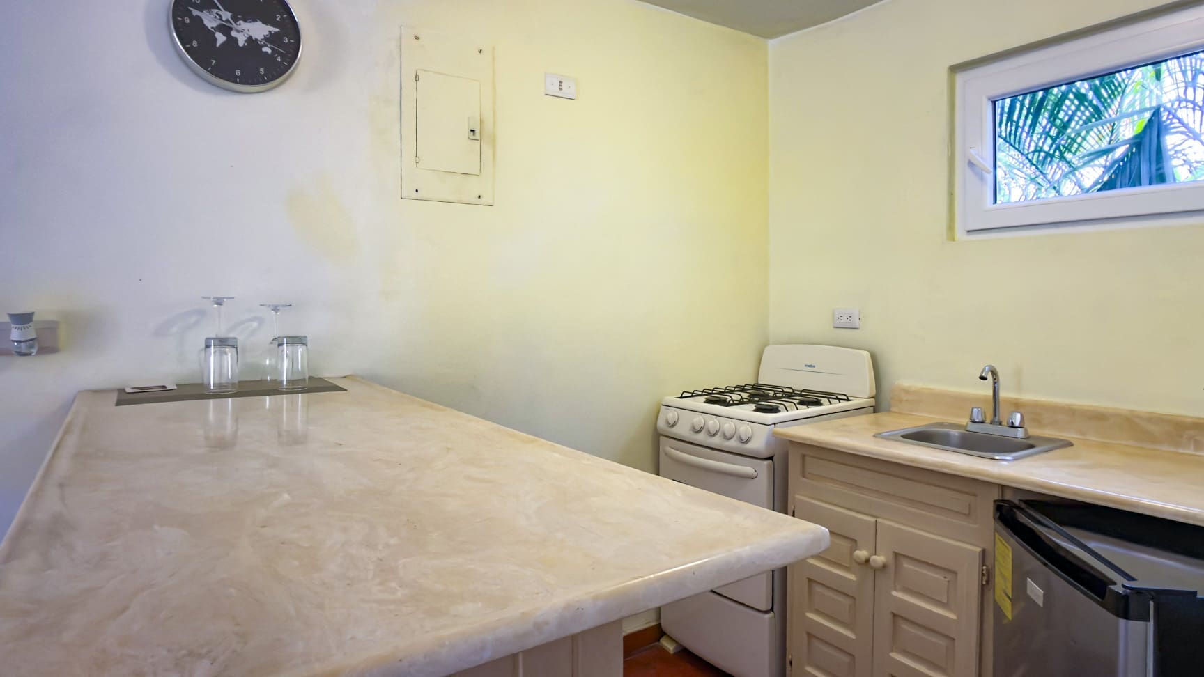 buyDRproperty Compact kitchen with a marble countertop, stove, sink, and small refrigerator. Sosua Real Estate