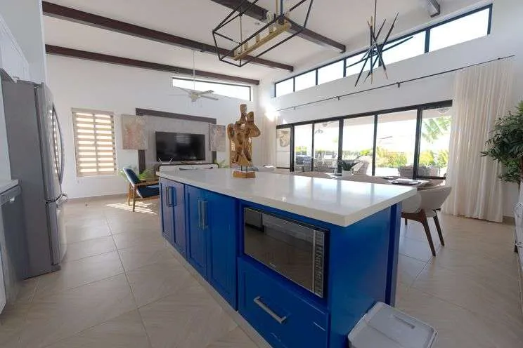 buyDRproperty Modern blue kitchen island with microwave and living area in background Sosua Real Estate