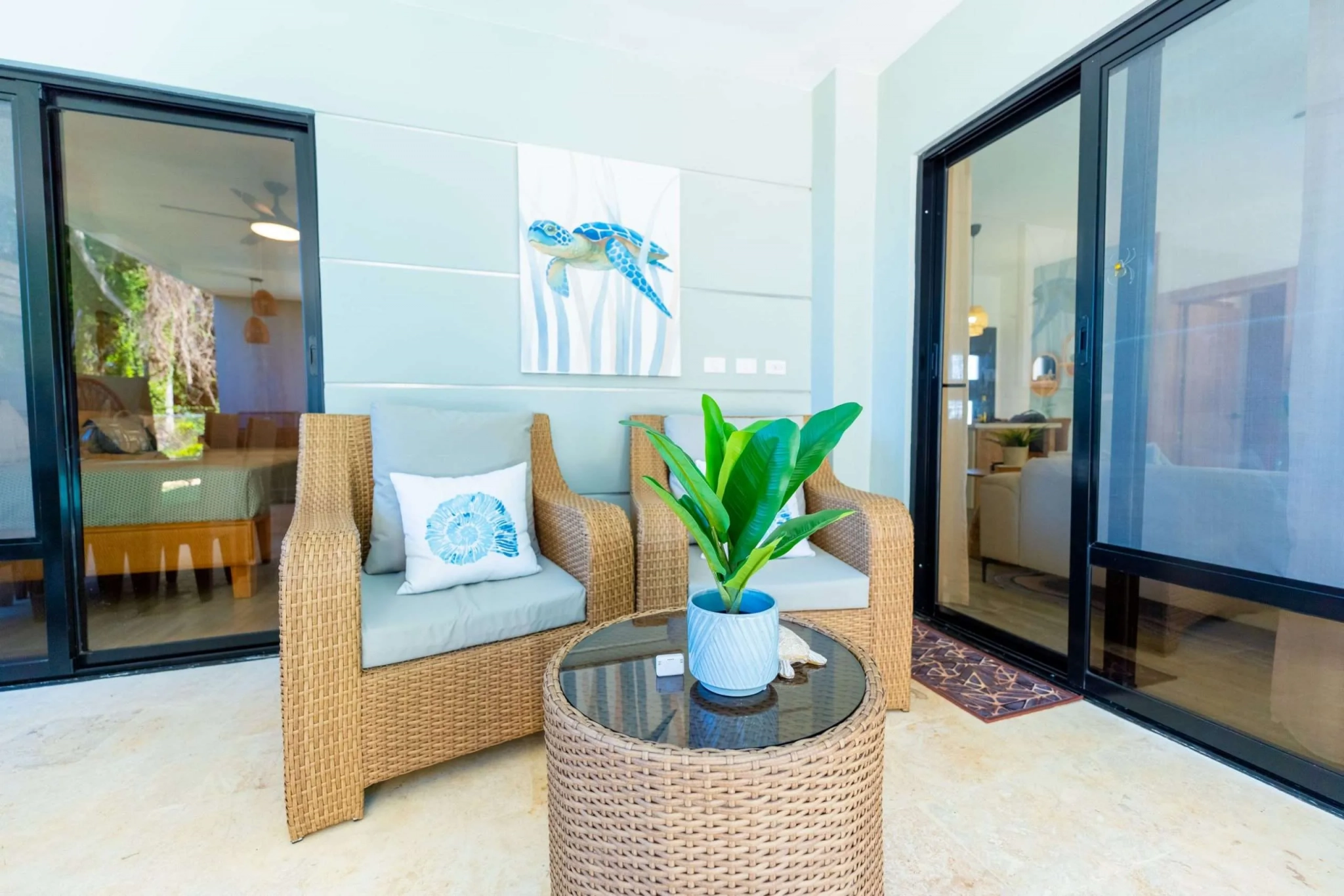 buyDRproperty Wicker chairs and table on a patio with sliding glass doors and sea turtle art. Sosua Real Estate