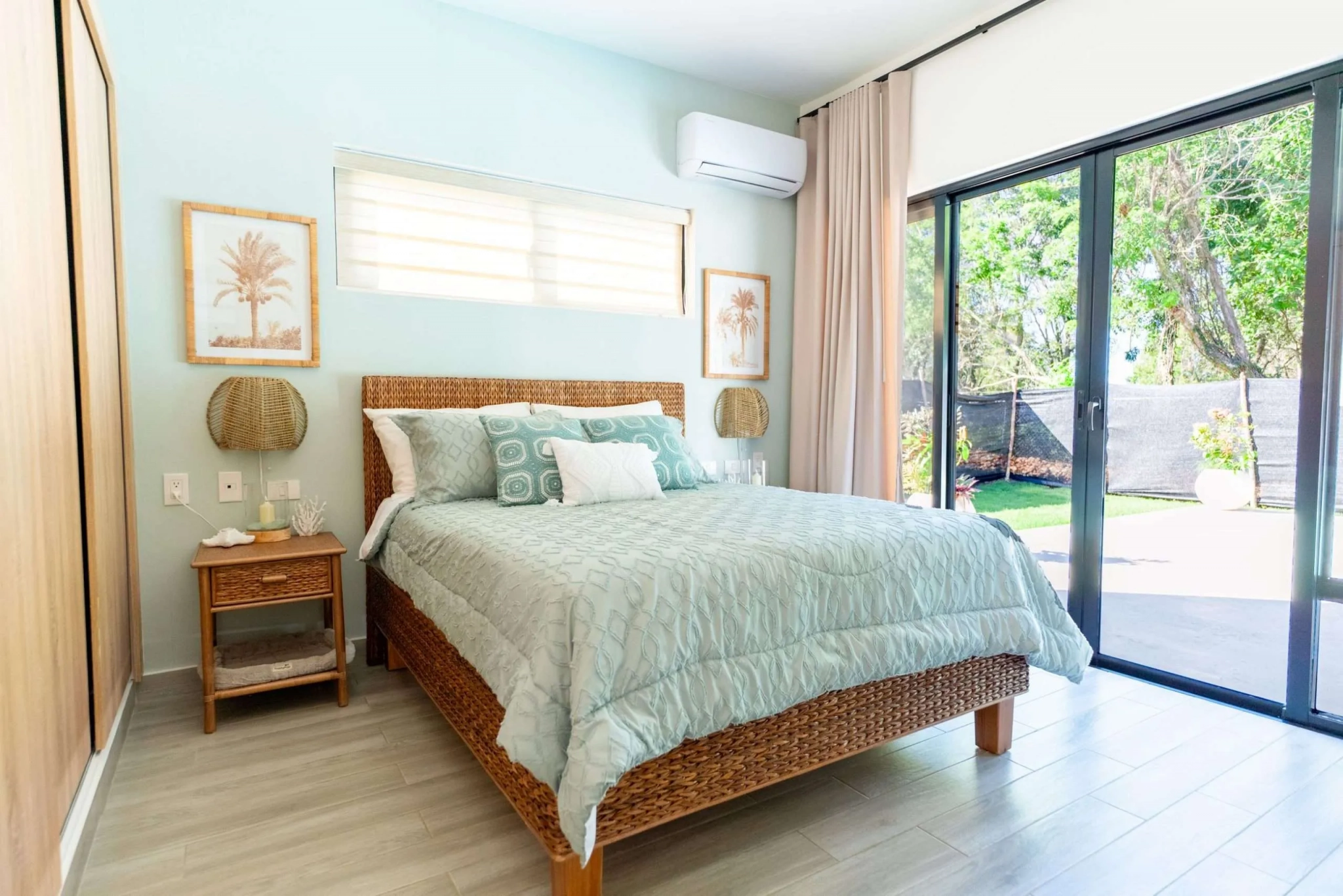 buyDRproperty Serene bedroom with a king-size bed, tropical art, and sliding glass doors leading to a lush garden. Sosua Real Estate