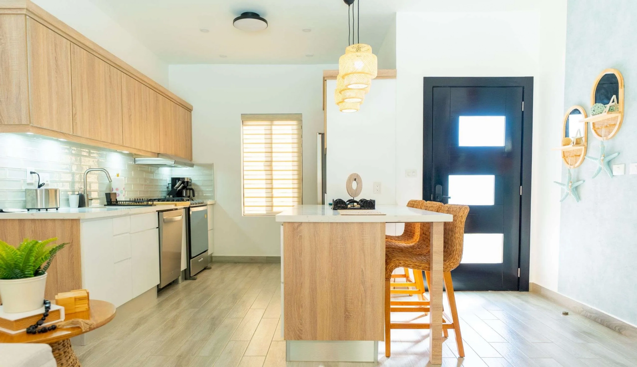 buyDRproperty Modern kitchen with light wood cabinets, white countertops, and a breakfast bar with rattan stools. Sosua Real Estate