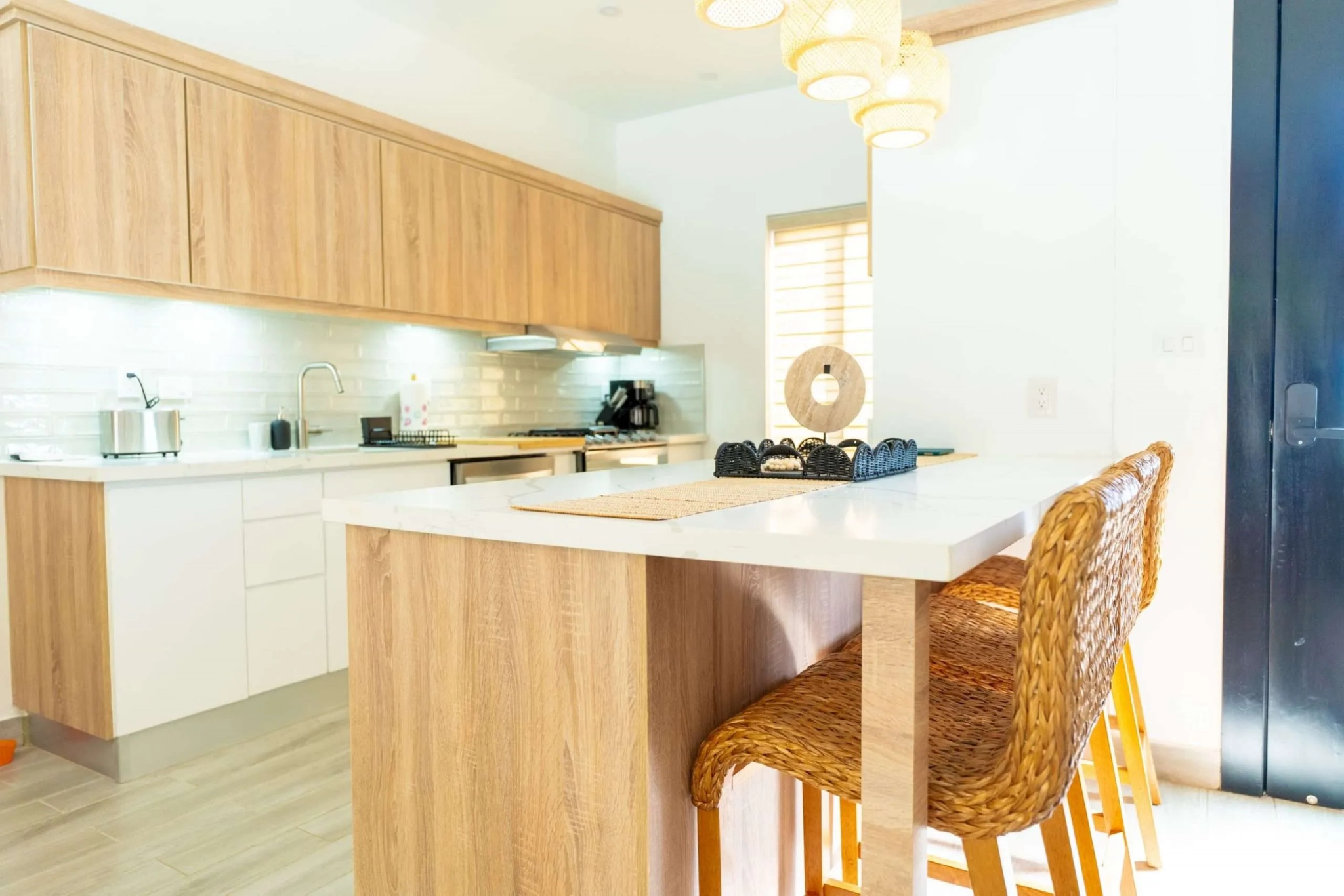 buyDRproperty Modern kitchen island with woven bar stools and pendant lighting. Sosua Real Estate
