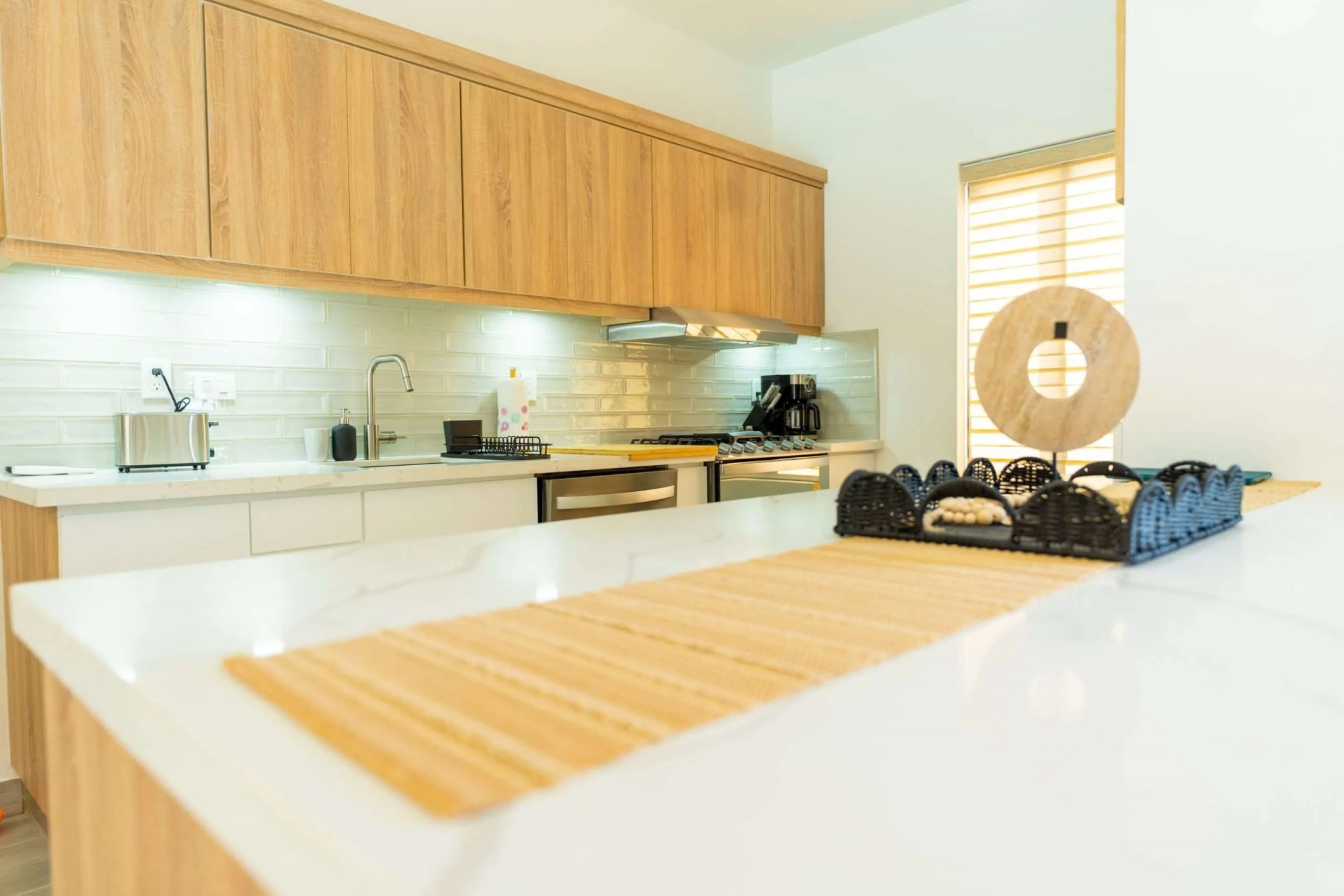 buyDRproperty Modern kitchen with light wood cabinets, white countertops, and stainless steel appliances. Sosua Real Estate