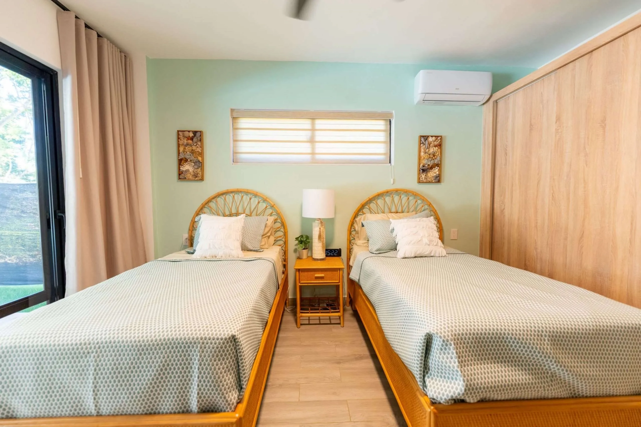buyDRproperty Two twin beds with light green patterned bedding in a bright bedroom with rattan headboards. Sosua Real Estate
