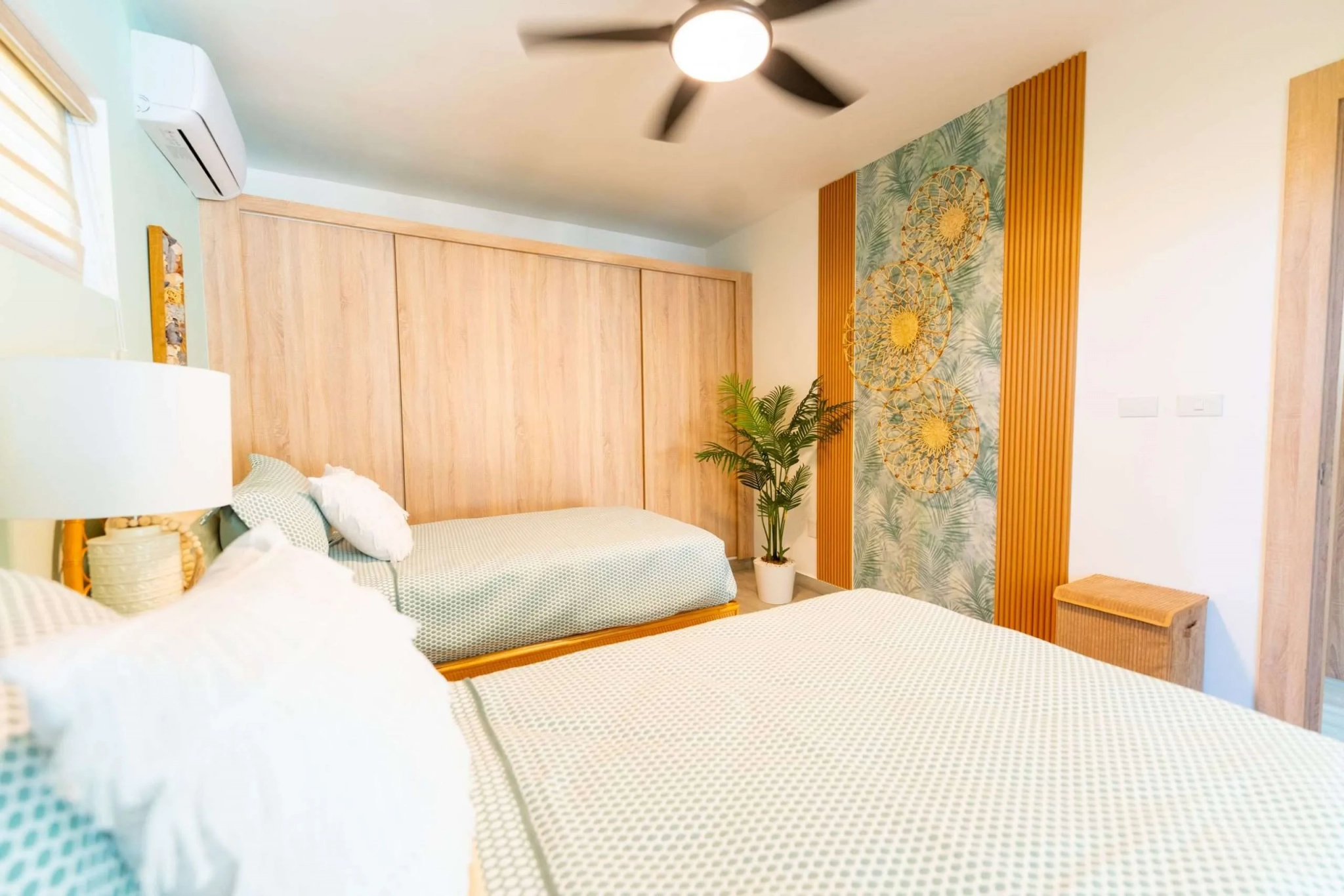 buyDRproperty Bright bedroom with two twin beds, tropical wallpaper, and a ceiling fan. Sosua Real Estate