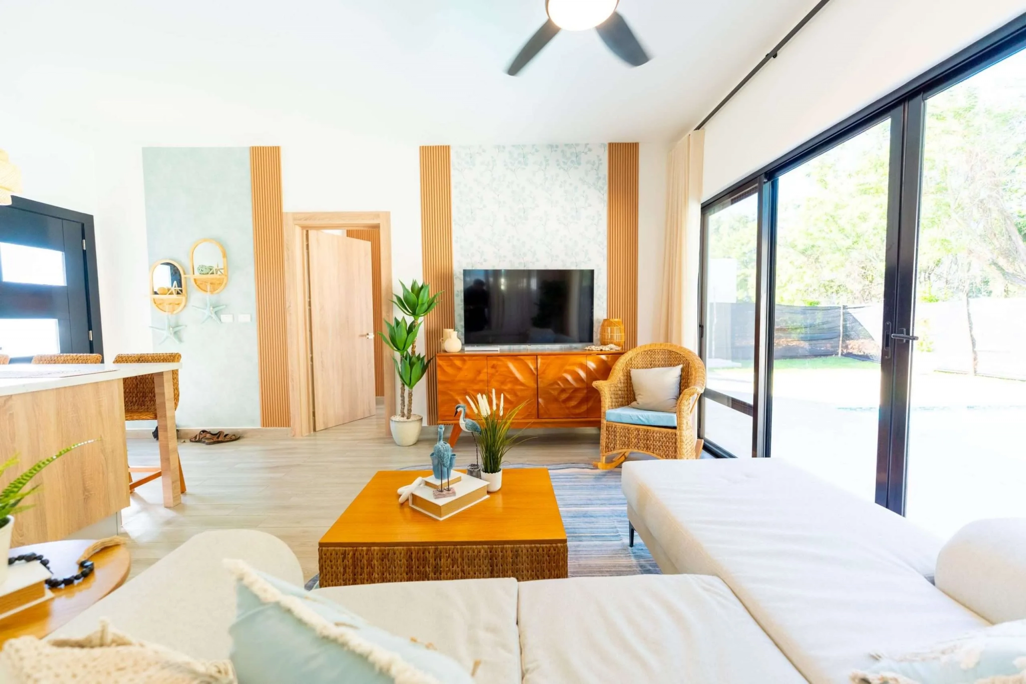 buyDRproperty Bright, modern living room with a sectional sofa, rattan chair, and large sliding doors to the outdoors. Sosua Real Estate