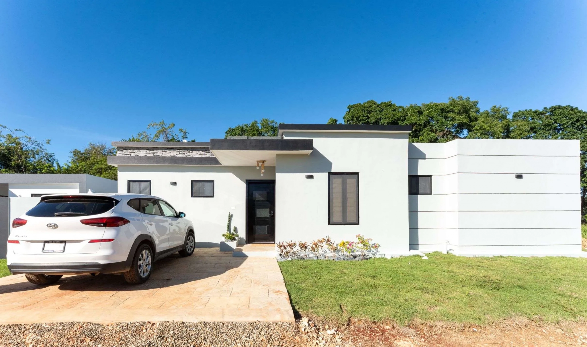 buyDRproperty Modern white house with a white SUV parked in the driveway. Sosua Real Estate
