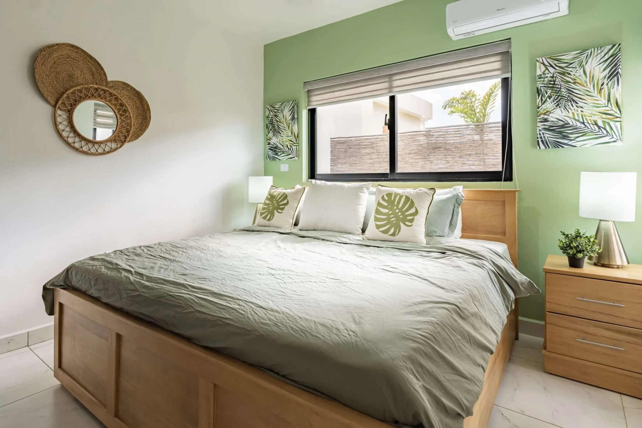 buyDRproperty Bright bedroom with king-size bed, tropical leaf art, and natural wood furniture. Sosua Real Estate