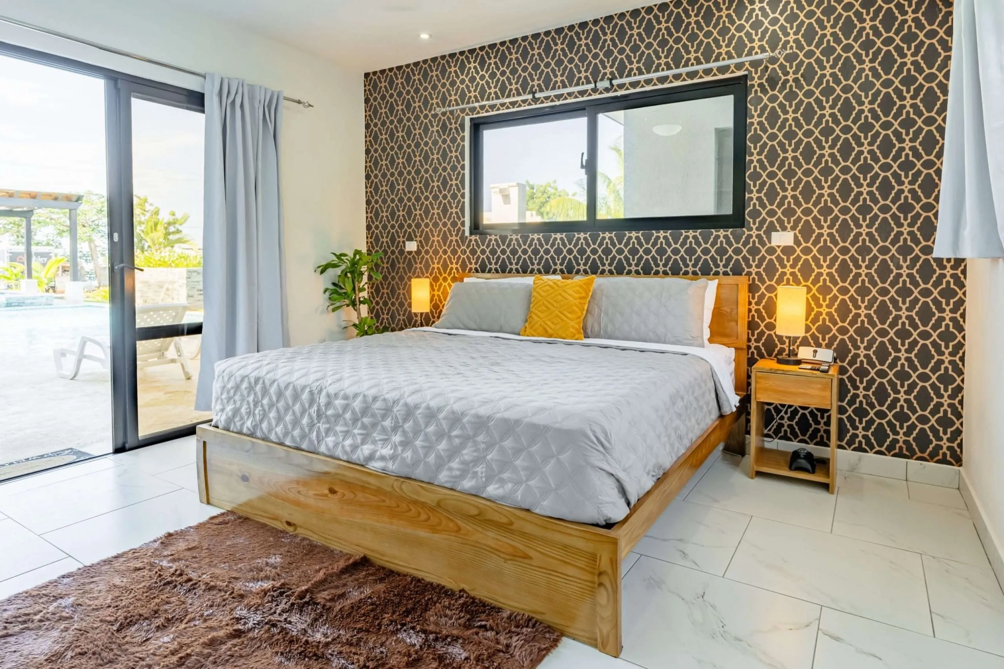 buyDRproperty Modern bedroom with king-size bed, patterned wallpaper, and pool view Sosua Real Estate