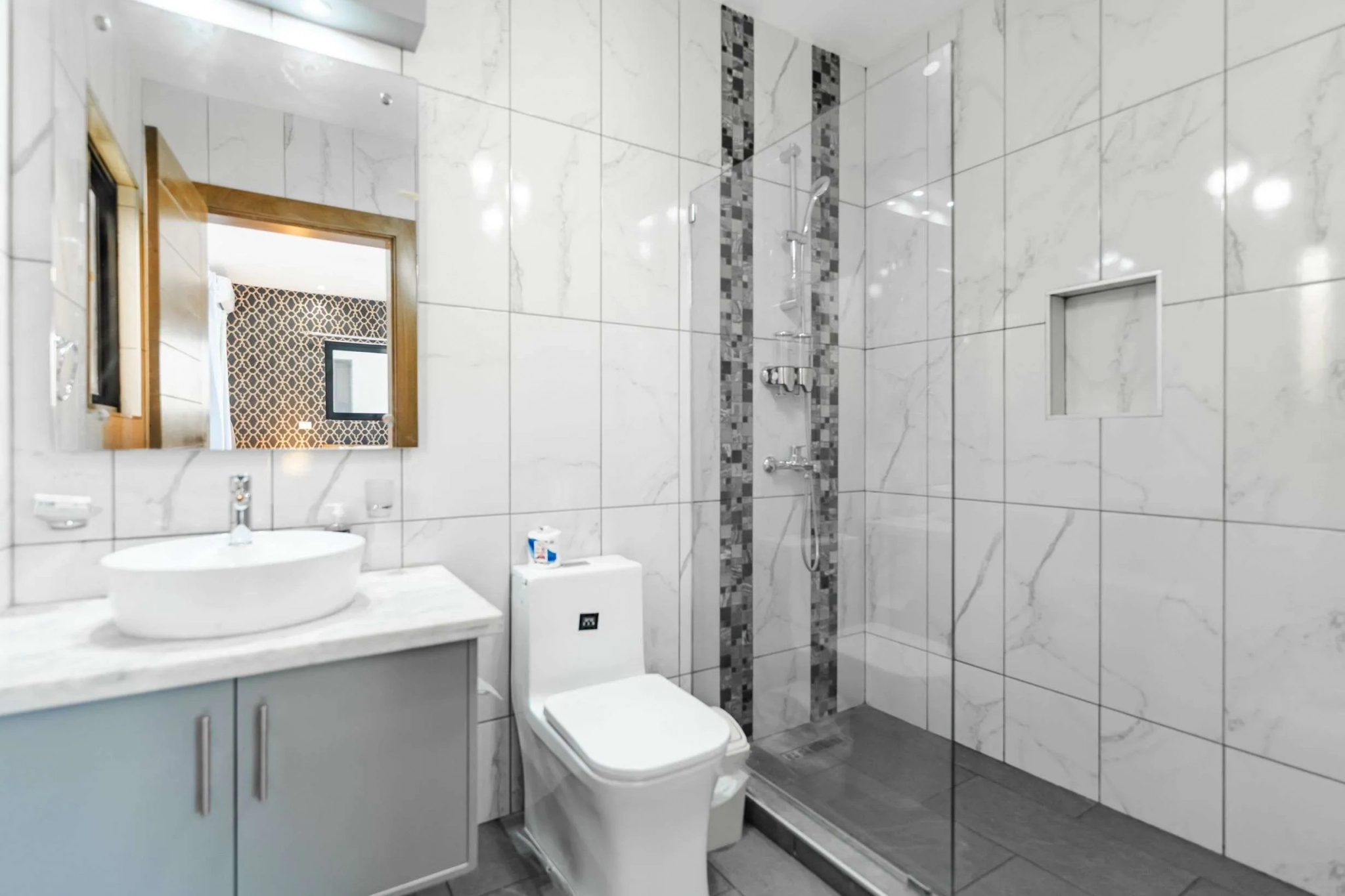 buyDRproperty Modern bathroom with white marble tiles, glass shower, and vanity Sosua Real Estate