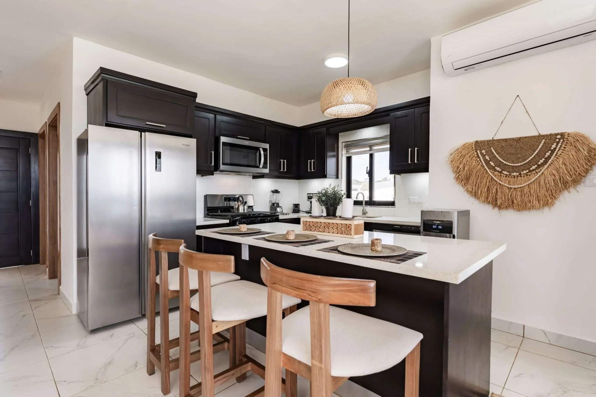 buyDRproperty Modern dark wood kitchen with island, stainless steel appliances, and pendant light. Sosua Real Estate