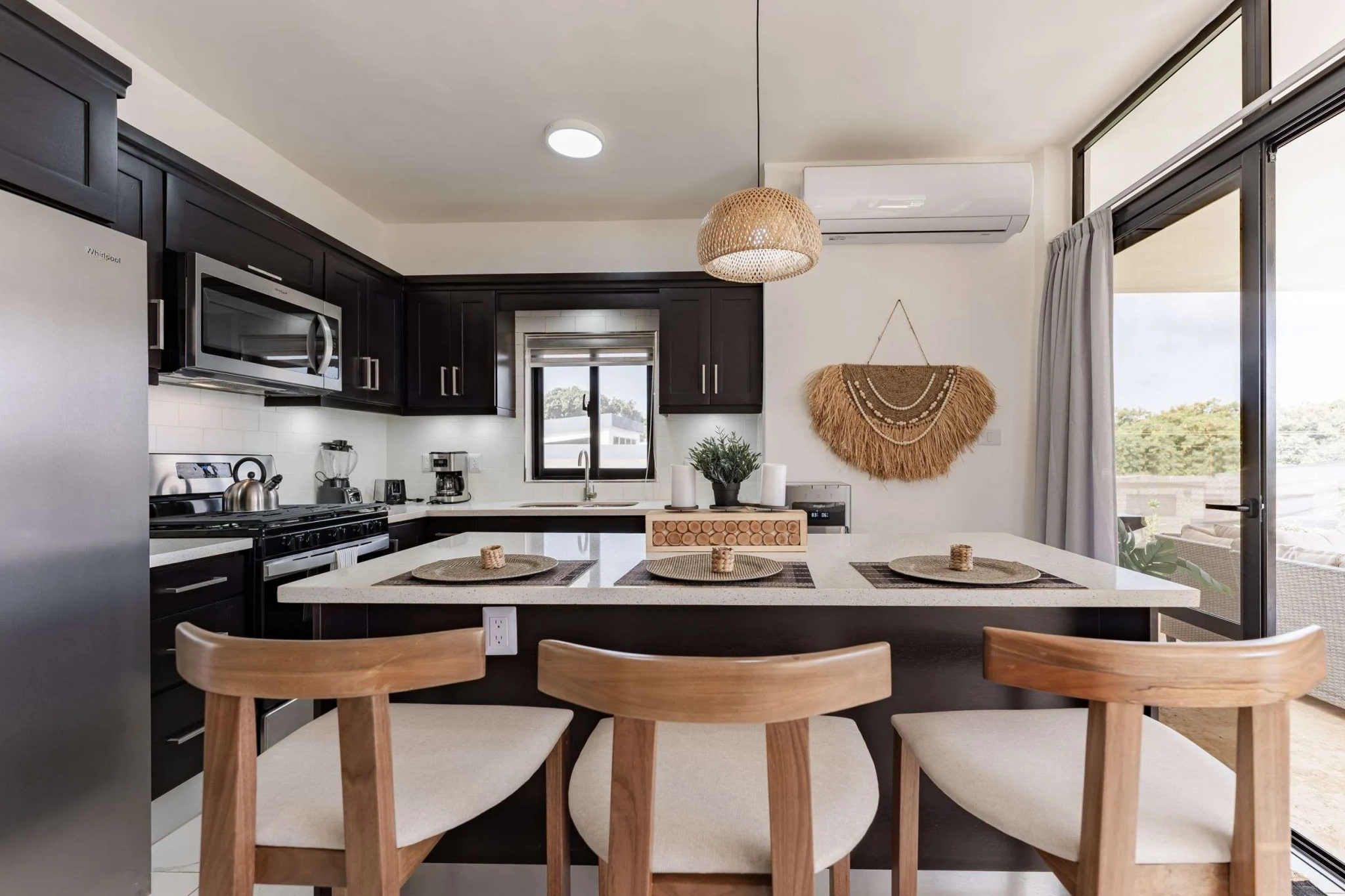 buyDRproperty Modern kitchen island with bar stools, dark cabinets, and stainless steel appliances. Sosua Real Estate