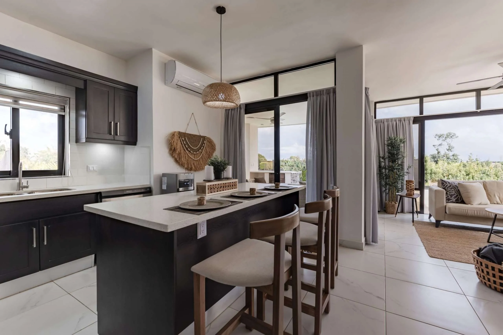 buyDRproperty Modern kitchen with dark cabinets, island seating, and natural light from patio doors. Sosua Real Estate