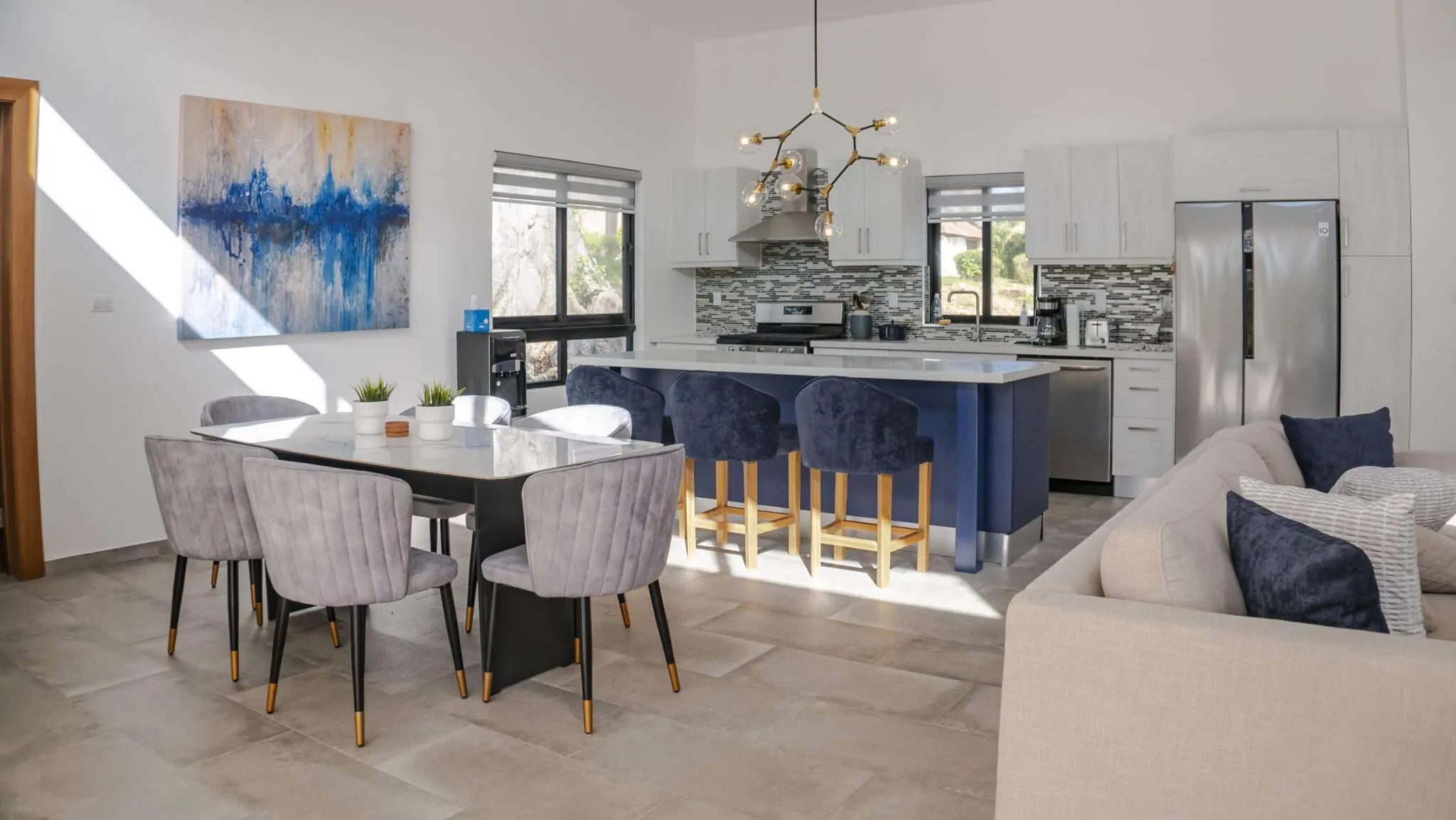 buyDRproperty Modern open-plan dining and kitchen area with island seating and abstract art. Sosua Real Estate