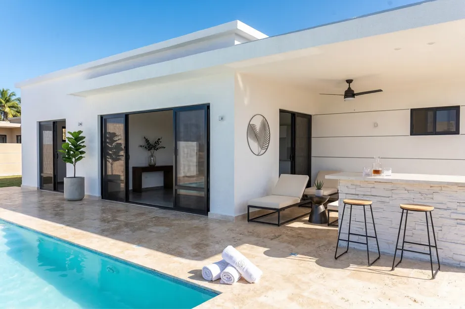 buyDRproperty Modern white villa with swimming pool, outdoor bar, and lounge chairs Sosua Real Estate