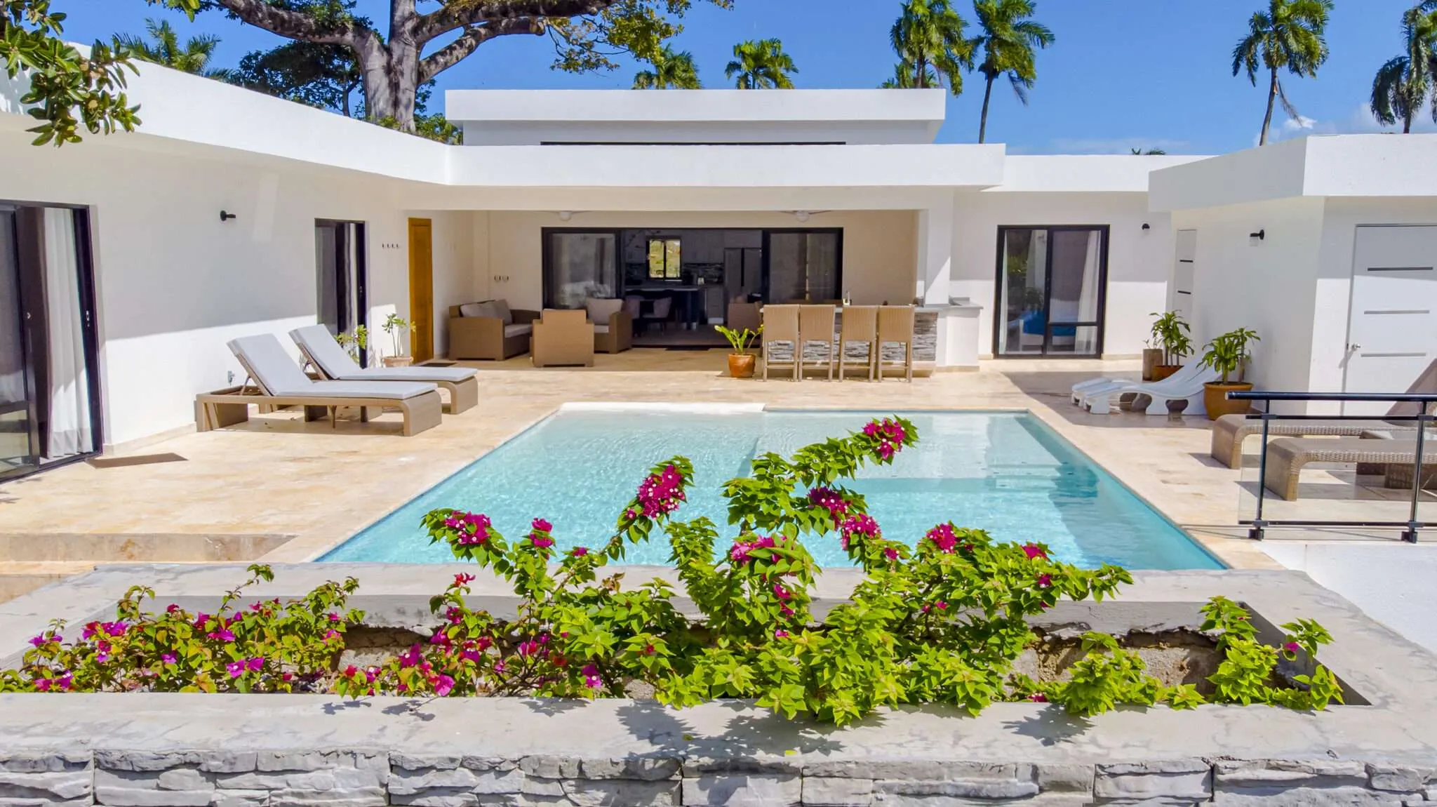 buyDRproperty Modern white villa with a sparkling swimming pool and lush tropical plants. Sosua Real Estate