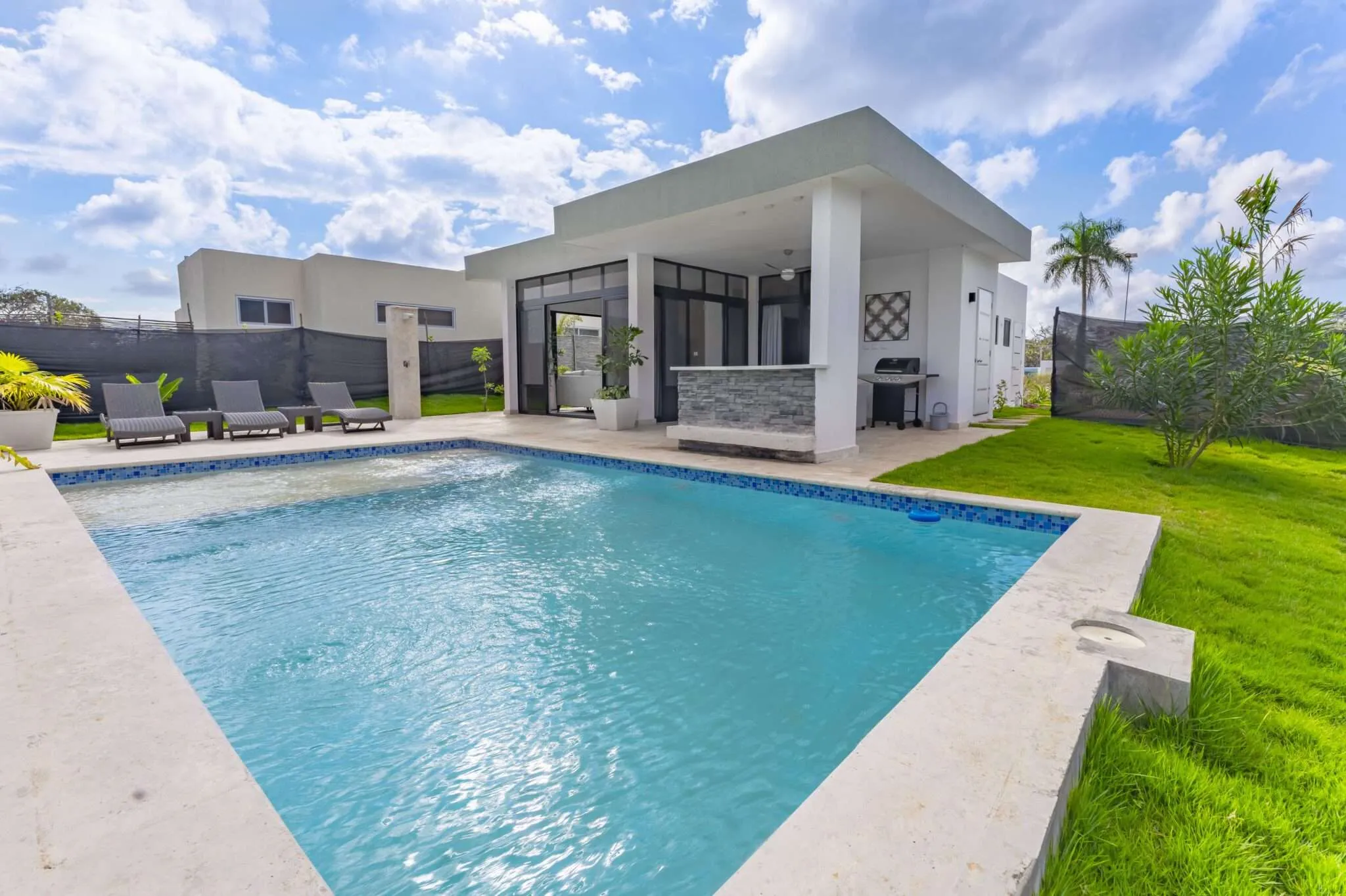 buyDRproperty Modern villa with swimming pool, outdoor bar, and grill in sunny weather Sosua Real Estate