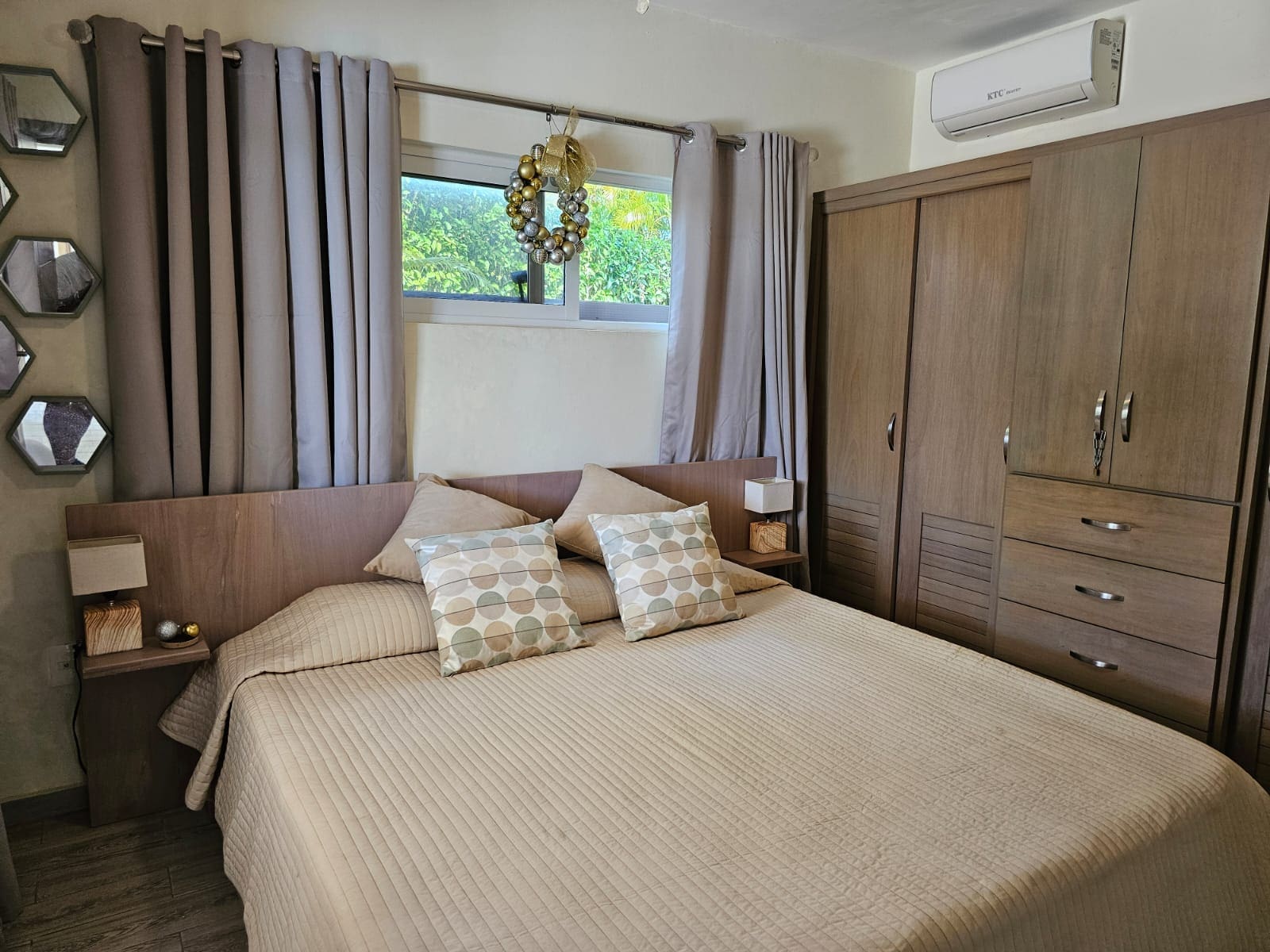 buyDRproperty Cozy bedroom with a large bed, wooden wardrobe, and window decorated with a wreath. Sosua Real Estate