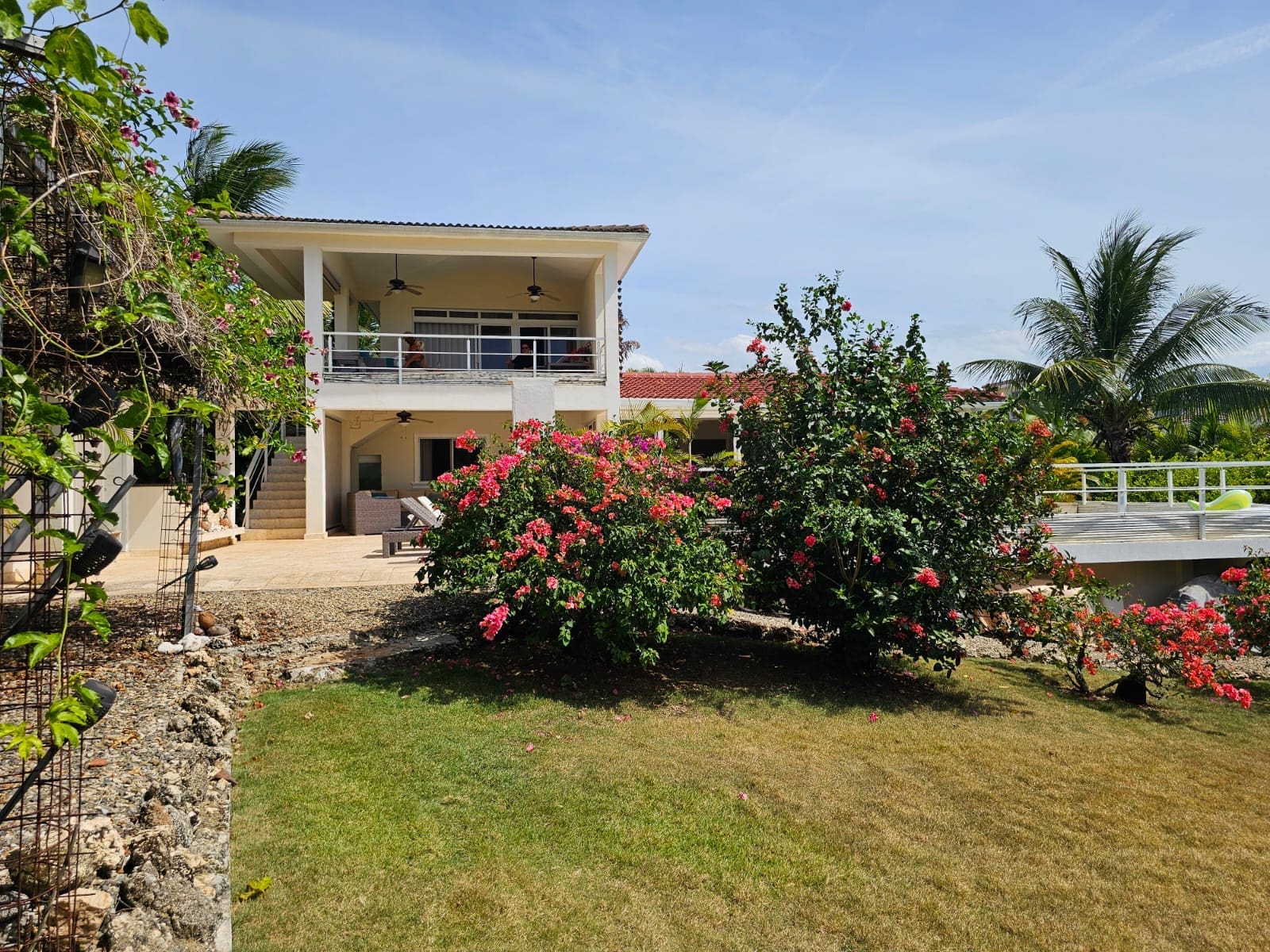 buyDRproperty Tropical villa with vibrant pink bougainvillea and lush green lawn. Sosua Real Estate