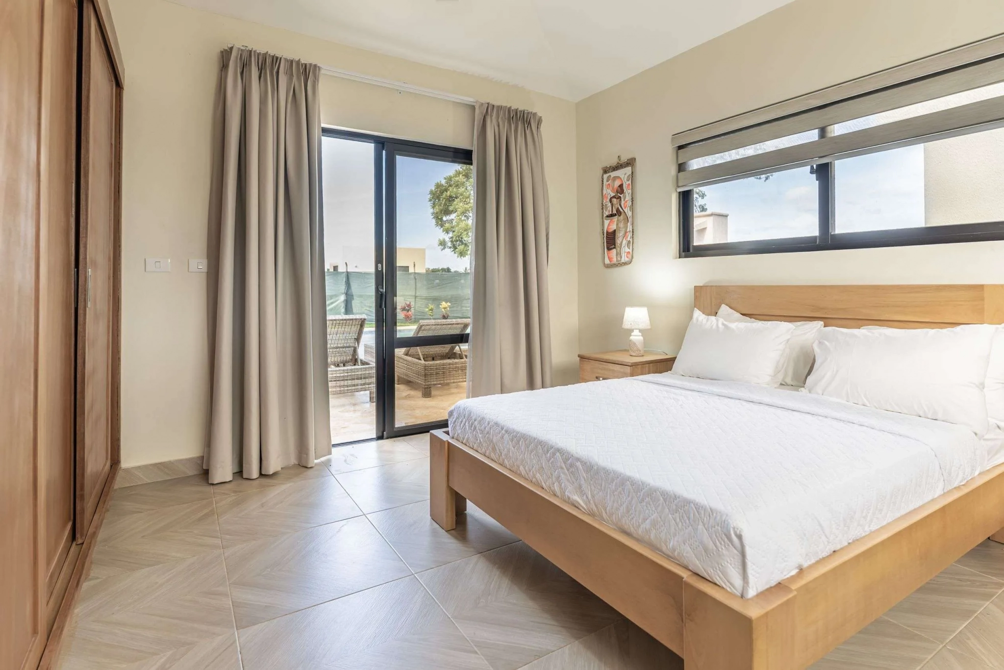buyDRproperty Modern bedroom with queen bed, sliding glass doors to patio, and wooden wardrobe. Sosua Real Estate