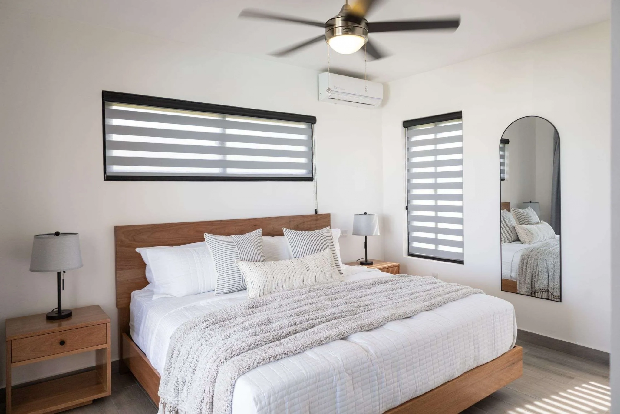 buyDRproperty Modern bedroom with king-size bed, white bedding, and striped pillows Sosua Real Estate