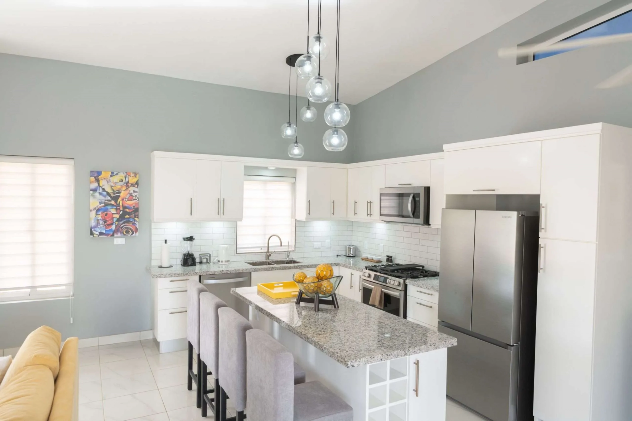 buyDRproperty Modern white kitchen with granite island, stainless steel appliances, and pendant lights. Sosua Real Estate