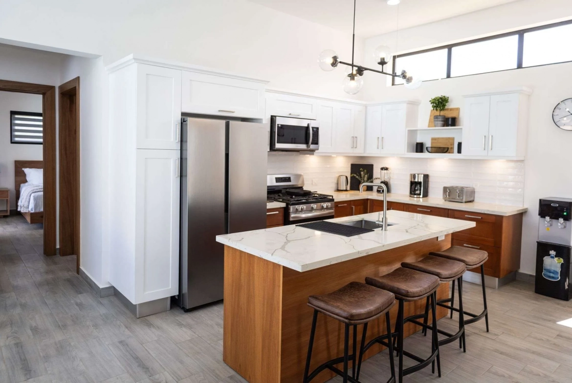 buyDRproperty Modern kitchen with stainless steel appliances, island with bar stools, and white cabinetry. Sosua Real Estate