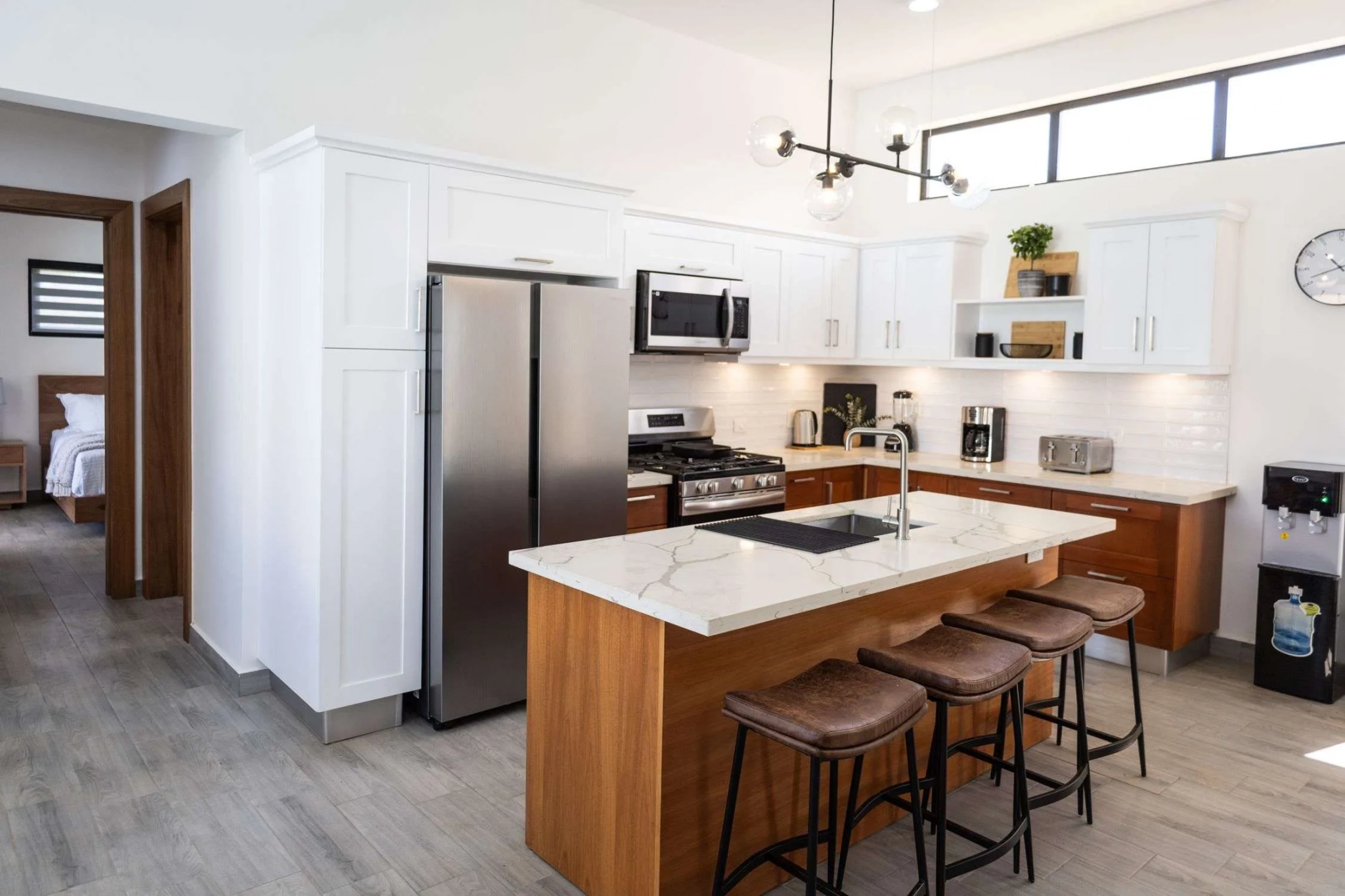 buyDRproperty Modern kitchen with stainless steel appliances, island with bar stools, and white cabinetry. Sosua Real Estate