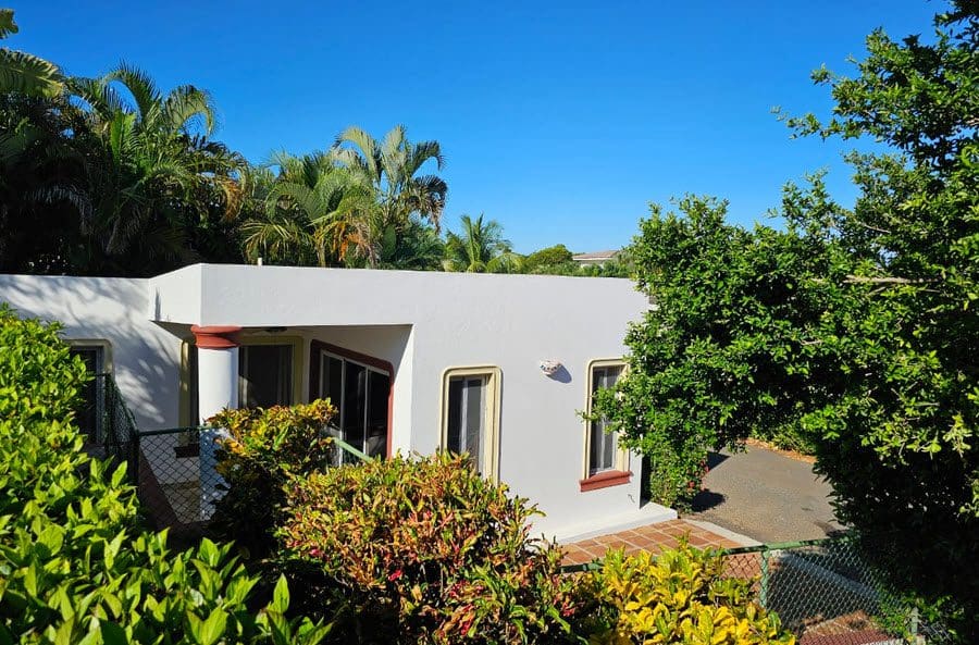 buyDRproperty Casa Linda Villa exterior with lush landscaping and blue sky. Sosua Real Estate