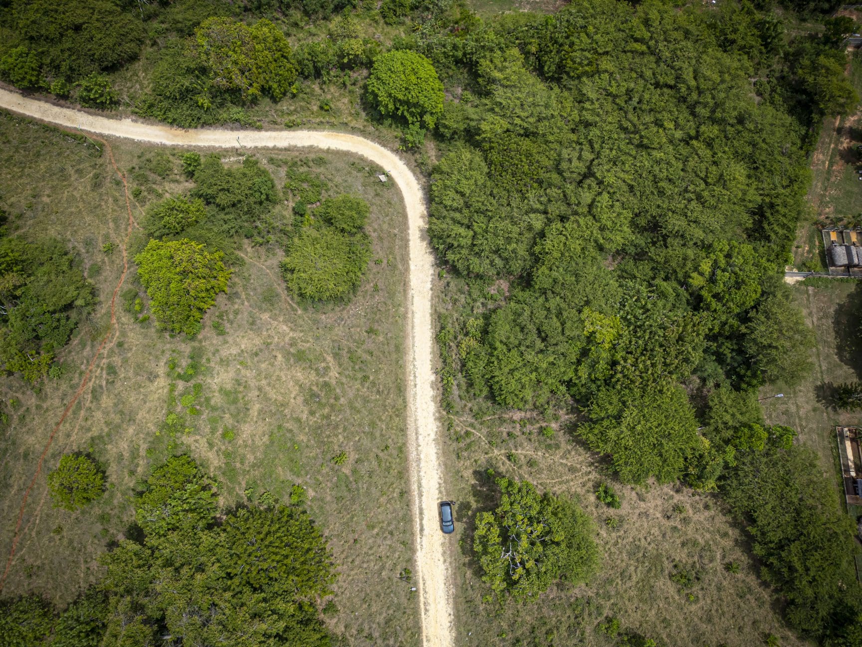 buyDRproperty Aerial view of a dirt road winding through lush green nature trails, captured by drone photography. Sosua Real Estate