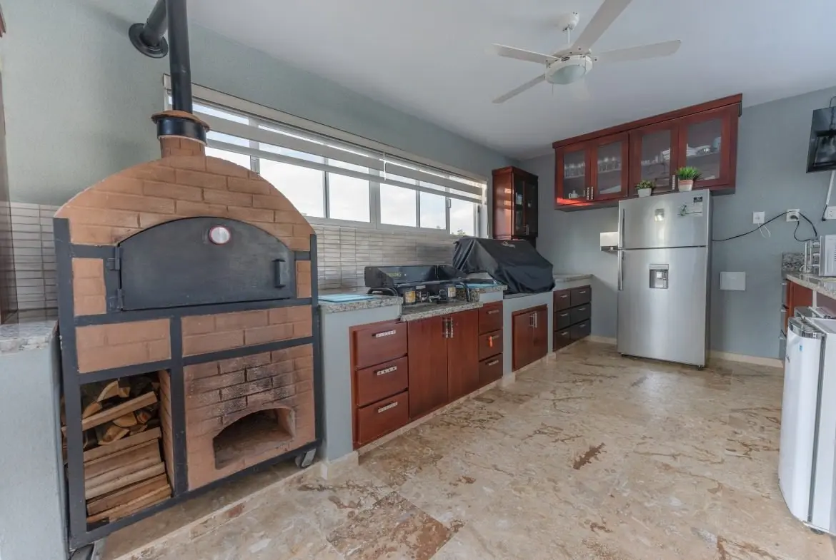 buyDRproperty Outdoor kitchen with brick pizza oven, stainless steel grill, and refrigerator. Sosua Real Estate
