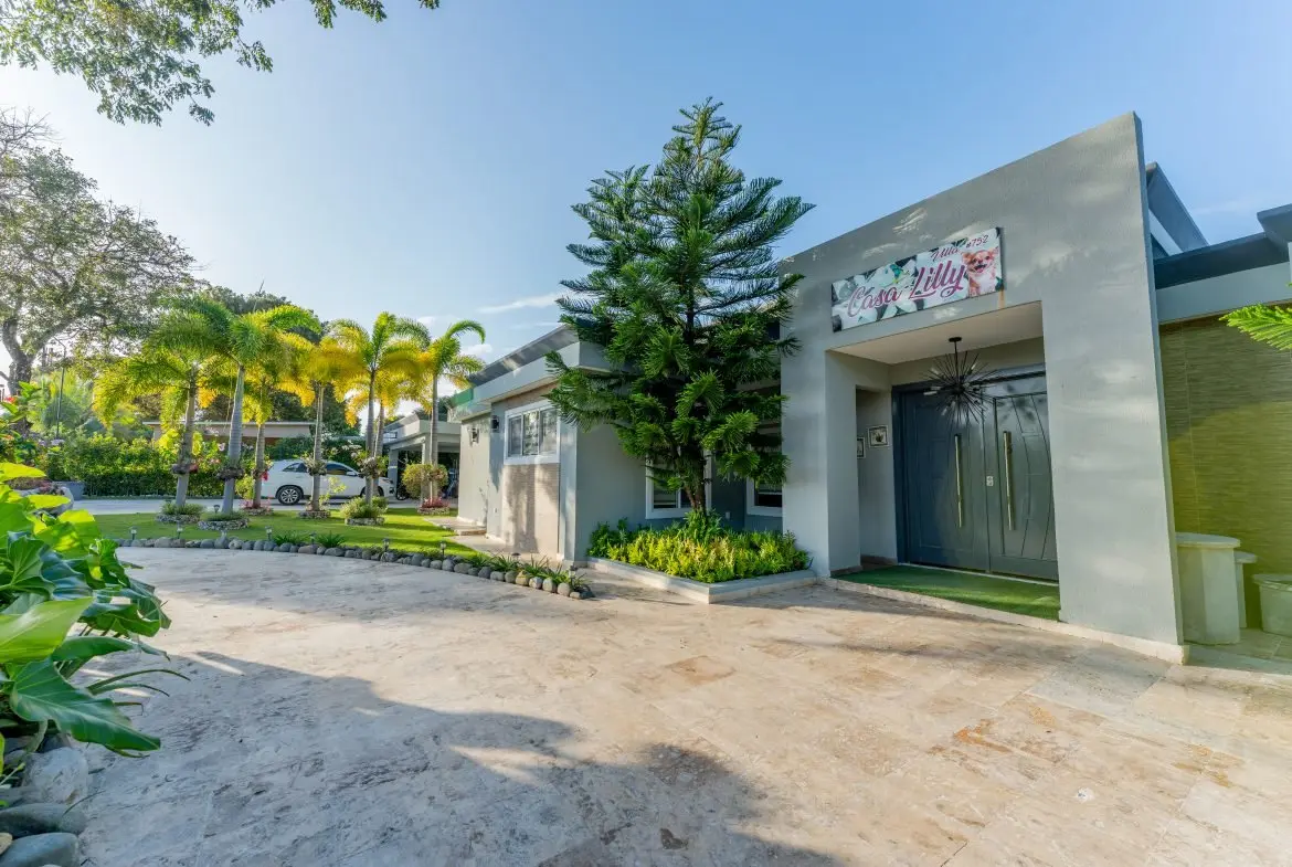 buyDRproperty Casa Lilly, a modern grey villa with palm trees and a manicured lawn. Sosua Real Estate