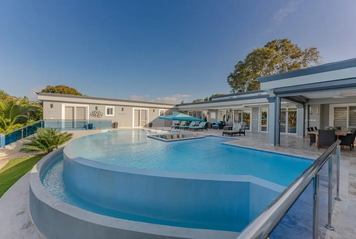 buyDRproperty Modern luxury villa with large curved swimming pool and outdoor dining area Sosua Real Estate
